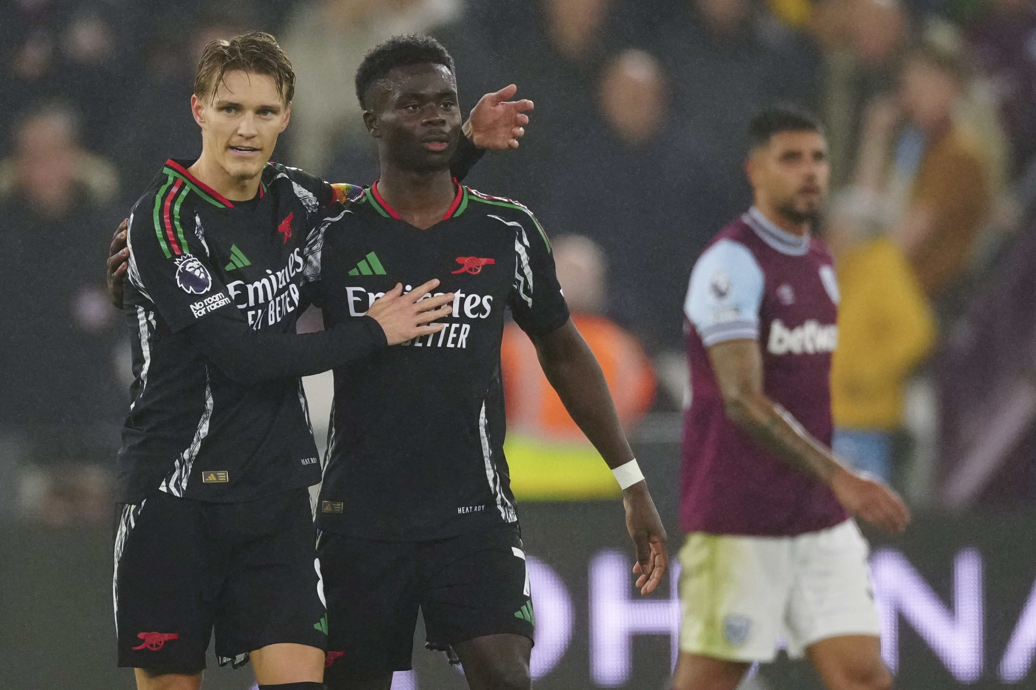 Arsenal's Martin Odegaard, left, celebrates with Arsenal's Bukayo Saka after scoring his side's third goal during the English Premier League soccer match between West Ham and Arsenal at the London Stadium in London, Saturday, Nov. 30, 2024.