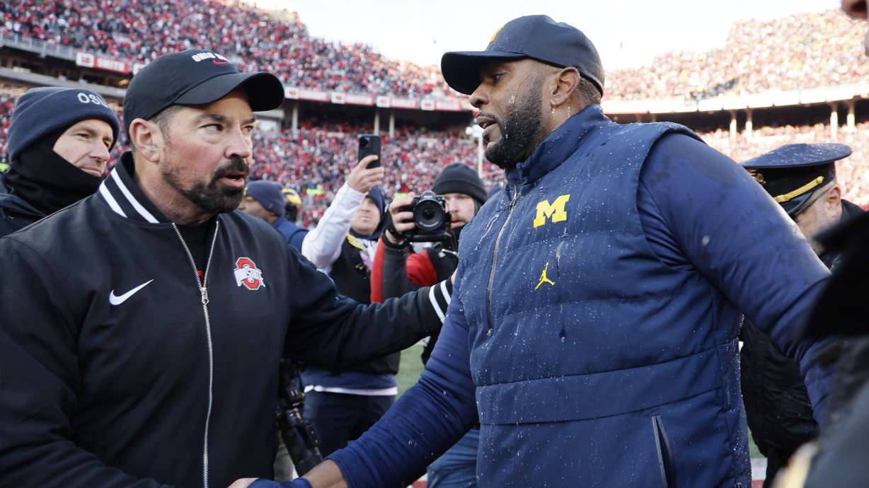 Ohio State head coach Ryan Day, left, and Michigan head coach Sherrone Moore shake hands Saturday in Columbus, Ohio. A fight where police were forced to use pepper spray broke out at the end of the game.