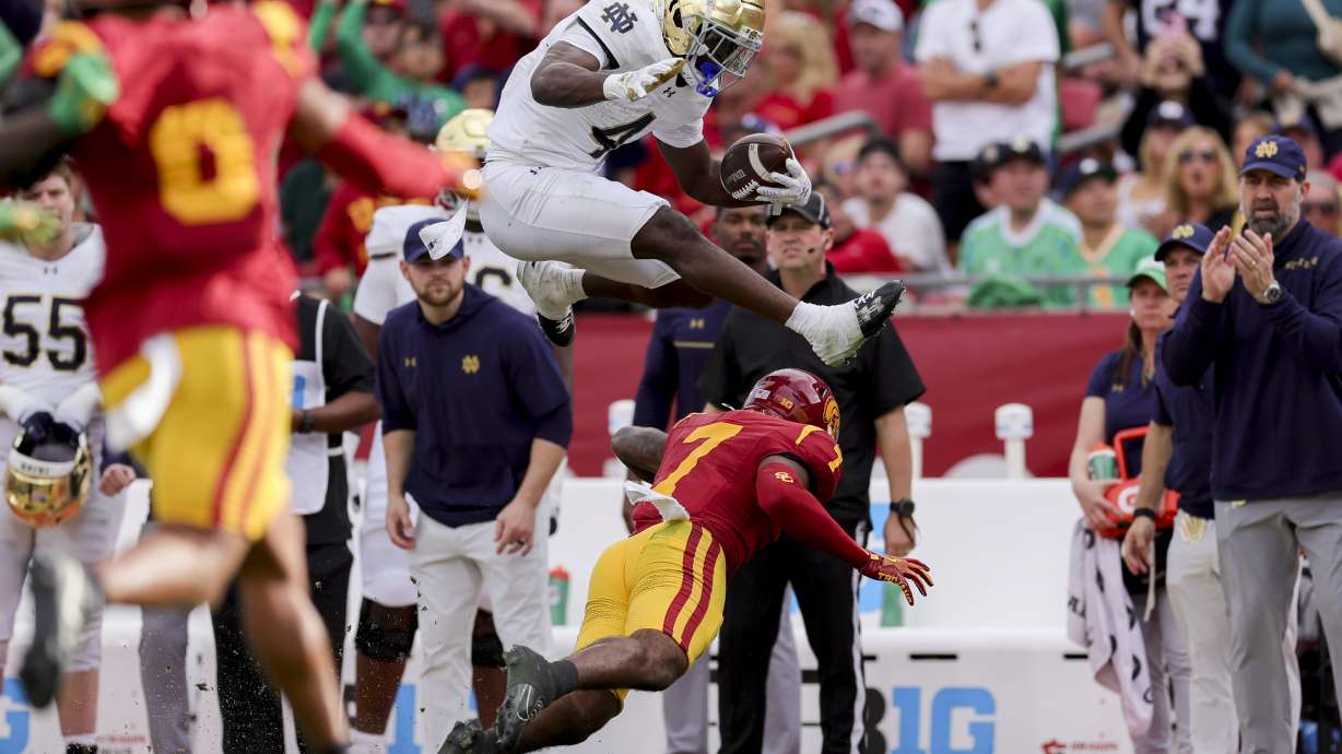 Notre Dame running back Jeremiyah Love, top, hurdles Southern California safety Kamari Ramsey during the first half of an NCAA football game, Saturday, Nov. 30, 2024, in Los Angeles.