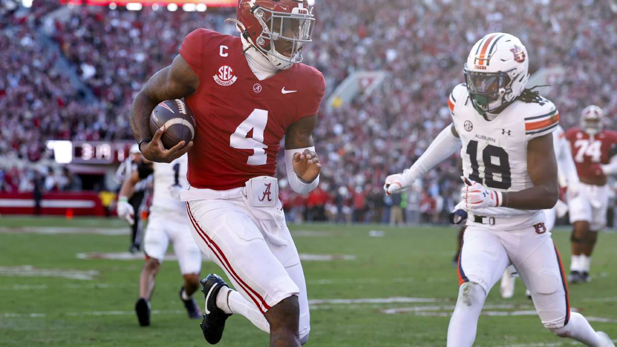 Alabama quarterback Jalen Milroe (4) carries the ball in for a touchdown as Auburn safety Kaleb Harris (18) defends during the first half of an NCAA college football game, Saturday, Nov. 30, 2024, in Tuscaloosa, Ala.
