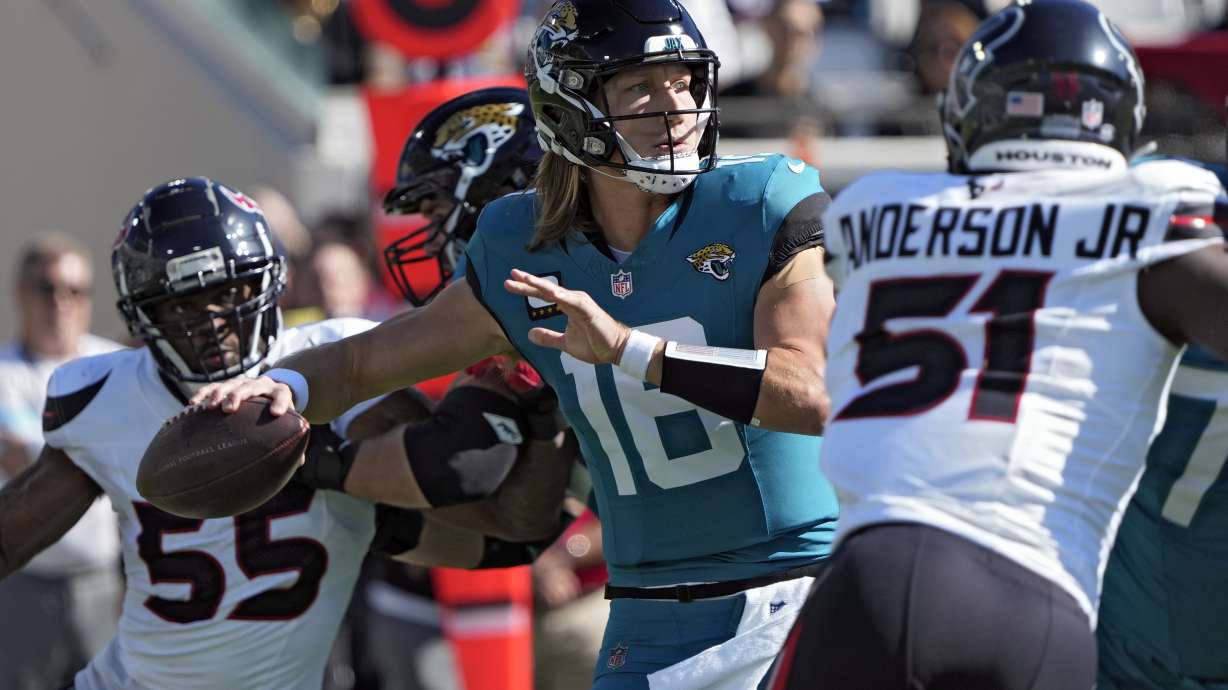 Jacksonville Jaguars quarterback Trevor Lawrence (16) throws a pass while he is pressured by Houston Texans defensive end Danielle Hunter (55) and defensive end Will Anderson Jr. (51) during the first half of an NFL football game Sunday, Dec. 1, 2024, in Jacksonville, Fla.