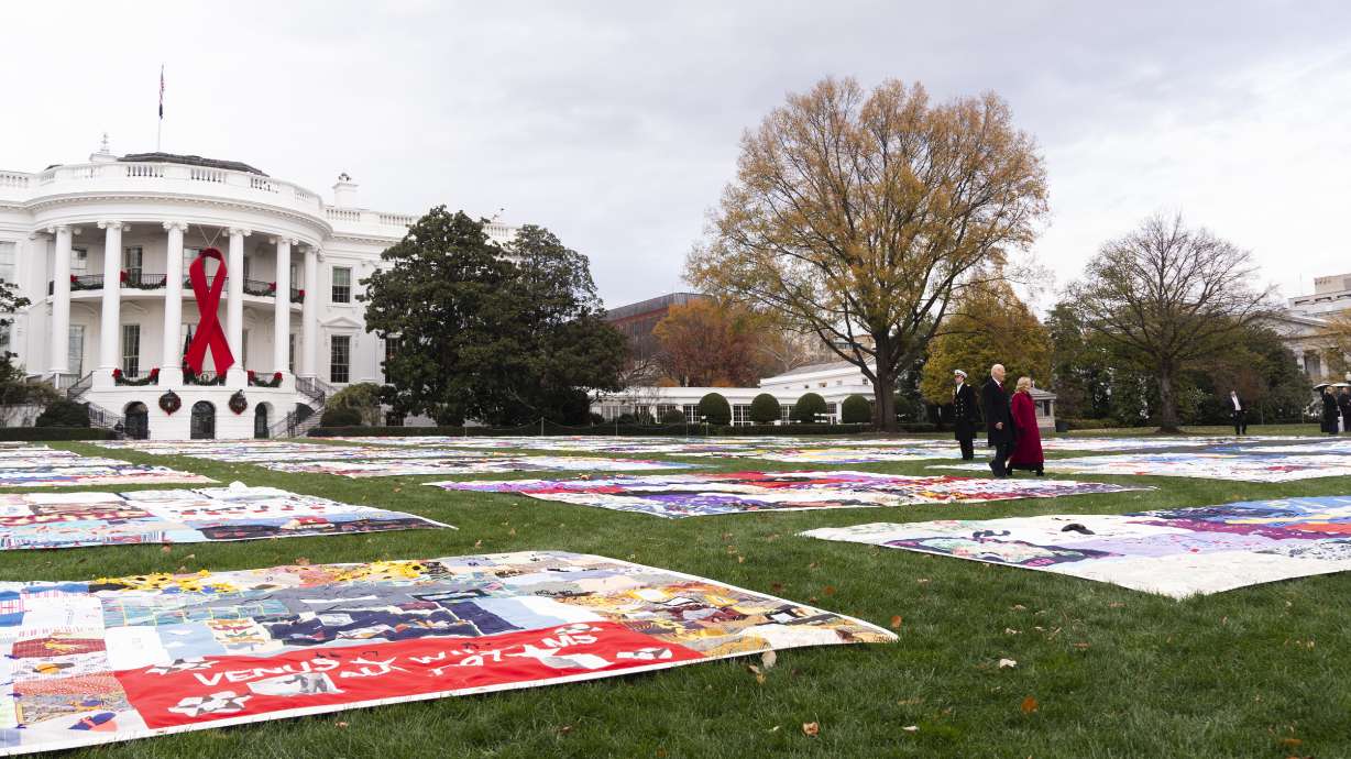 President Joe Biden and first lady Jill Biden walk between AIDS Memorial Quilts spread over the South Lawn of the White House during a ceremony to commemorate World AIDS Day with survivors, their families and advocates, Sunday, in Washington.
