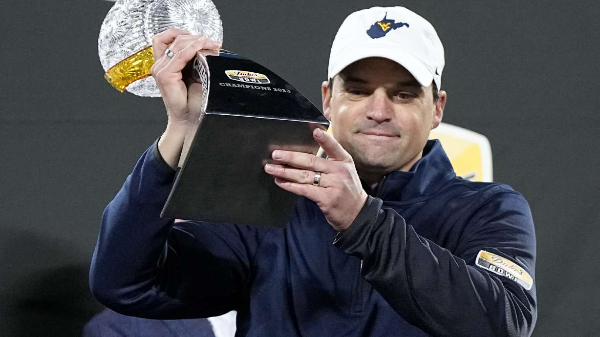 FILE - West Virginia head coach Neal Brown gets holds the trophy after their win against North Carolina in an NCAA college football game at the Duke's Mayo Bowl Wednesday, Dec. 27, 2023, in Charlotte, N.C.