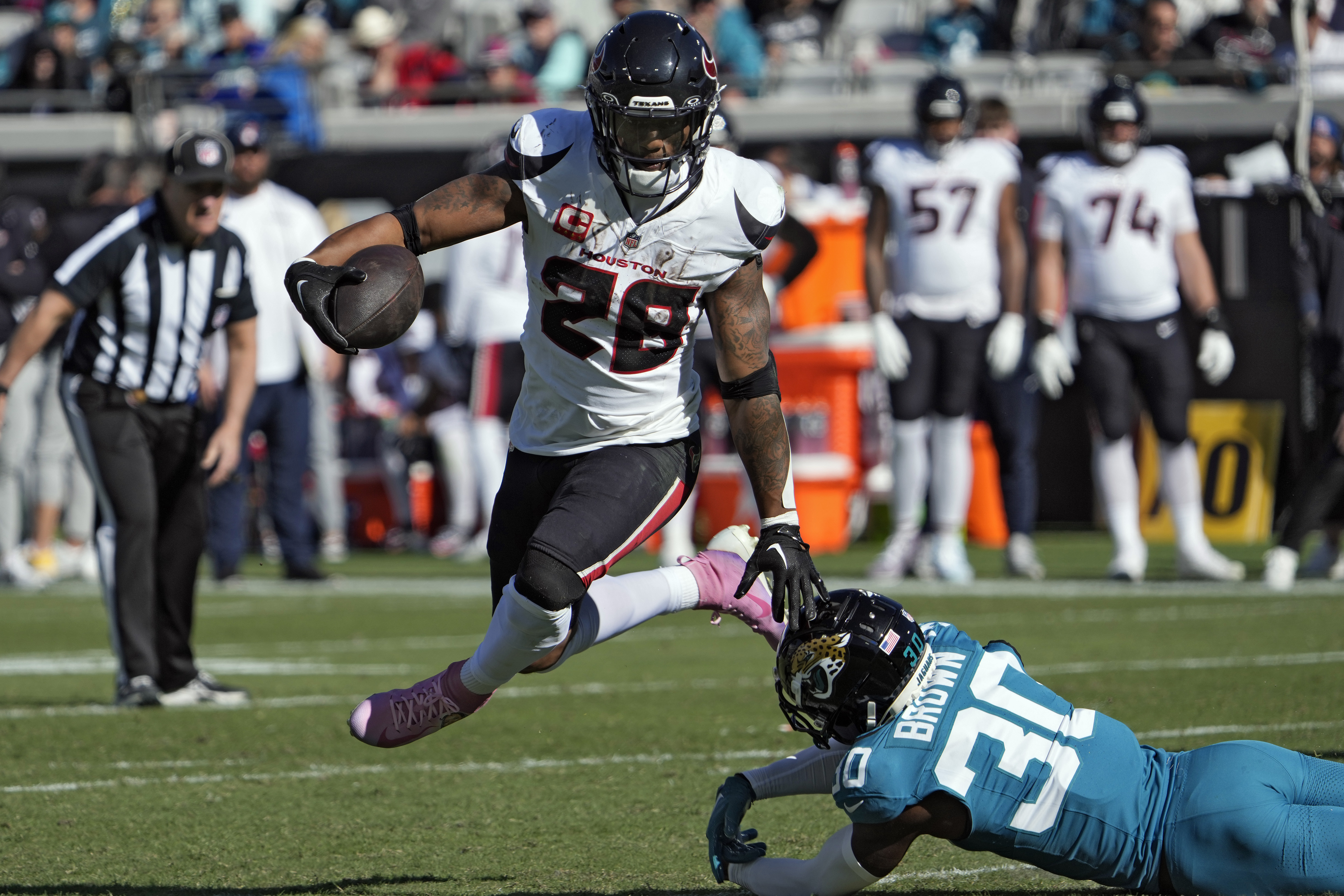 Houston Texans running back Joe Mixon (28) jumps over Jacksonville Jaguars cornerback Montaric Brown (30) on a run during the first half of an NFL football game, Sunday, Dec. 1, 2024, in Jacksonville, Fla.