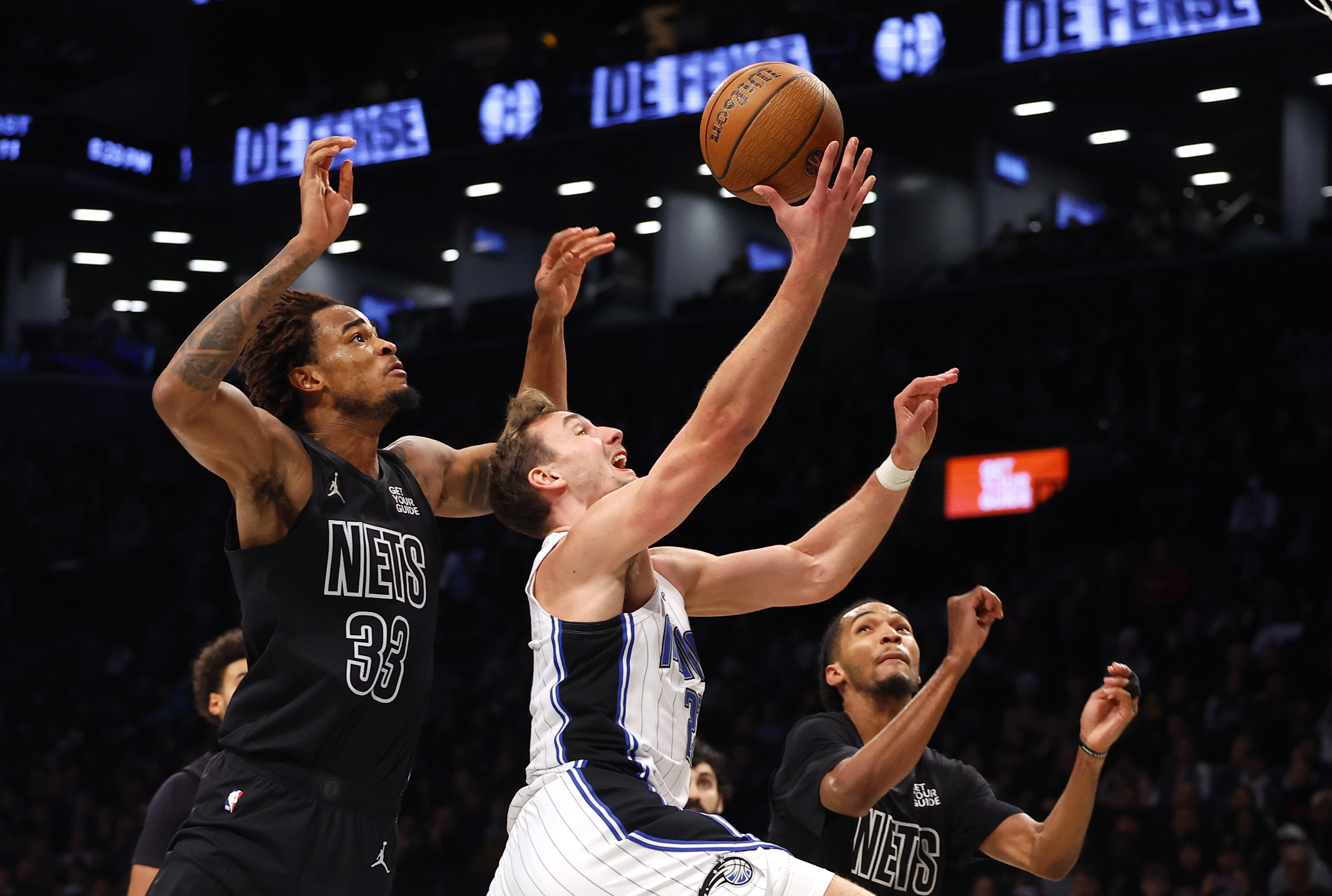 Orlando Magic forward Franz Wagner (22) drives to the basket against Brooklyn Nets center Nic Claxton (33) and forward Ziaire Williams (1) during the first half of an Emirates NBA Cup basketball game, Friday, Nov. 29, 2024, in New York.