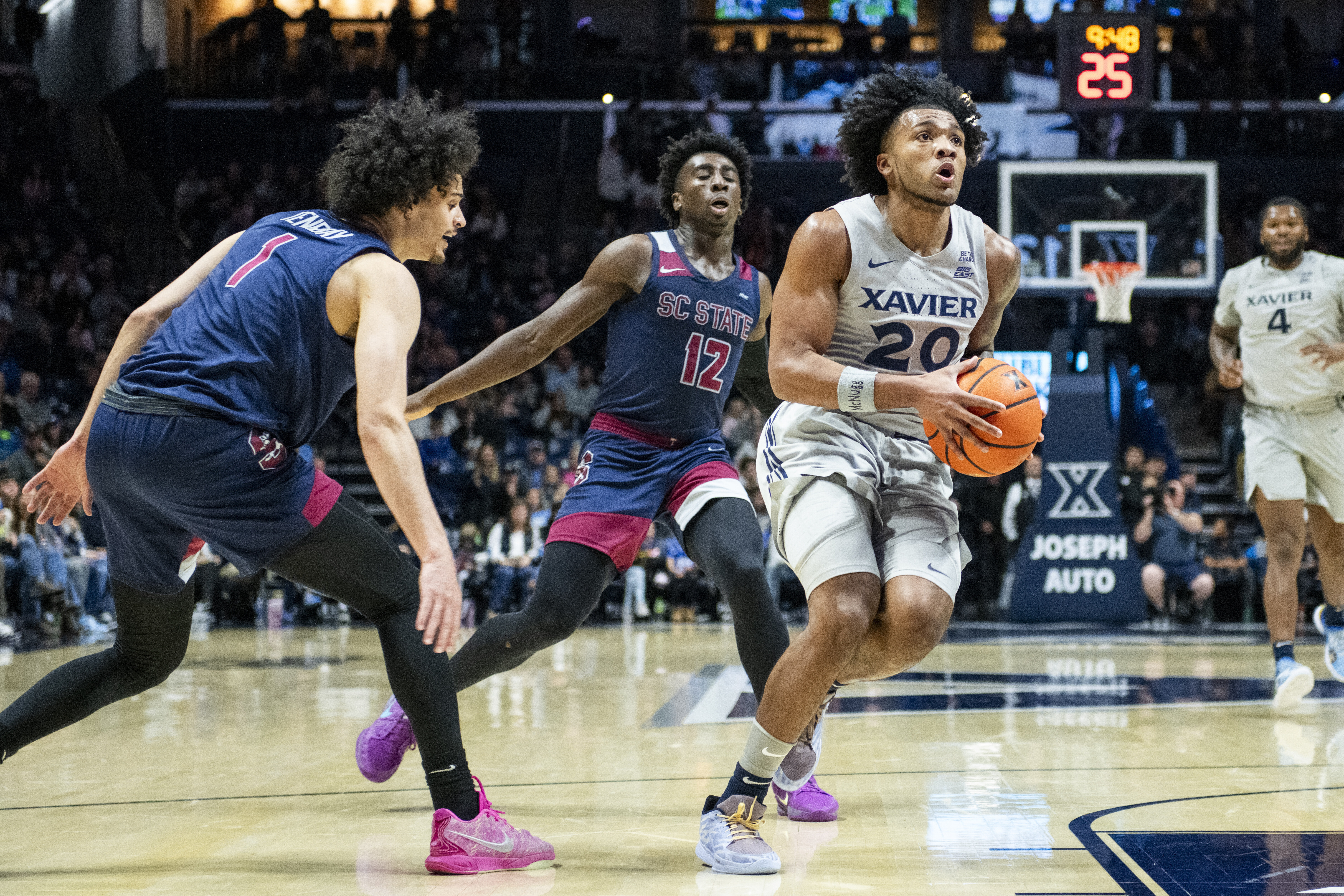 Xavier guard Dayvion McKnight (20) drives toward the basket as he is defended by South Carolina State players during the first half of an NCAA college basketball game Sunday, Dec. 1, 2024, in Cincinnati.