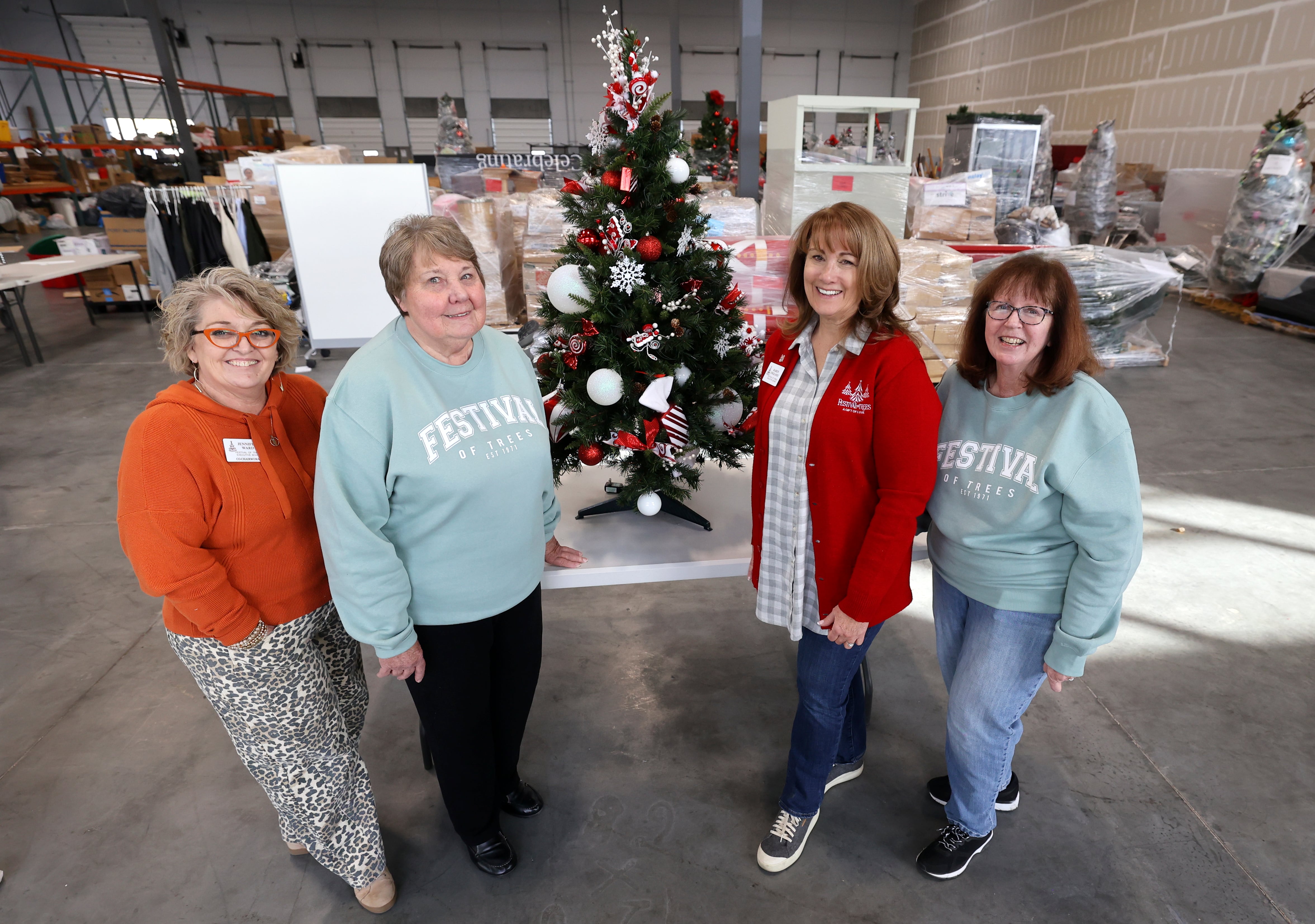 Jennifer Ward, Festival of Trees Executive Board co-chairwoman, Norma Jensen, Festival of Trees Alumni Board member, Karen England, Festival of Trees Alumni Board member, and Cathy Strunk, Festival of Trees Alumni Board member, pose for a photo by a tree they helped decorate at the Festival of Trees warehouse in South Salt Lake on Nov. 14.