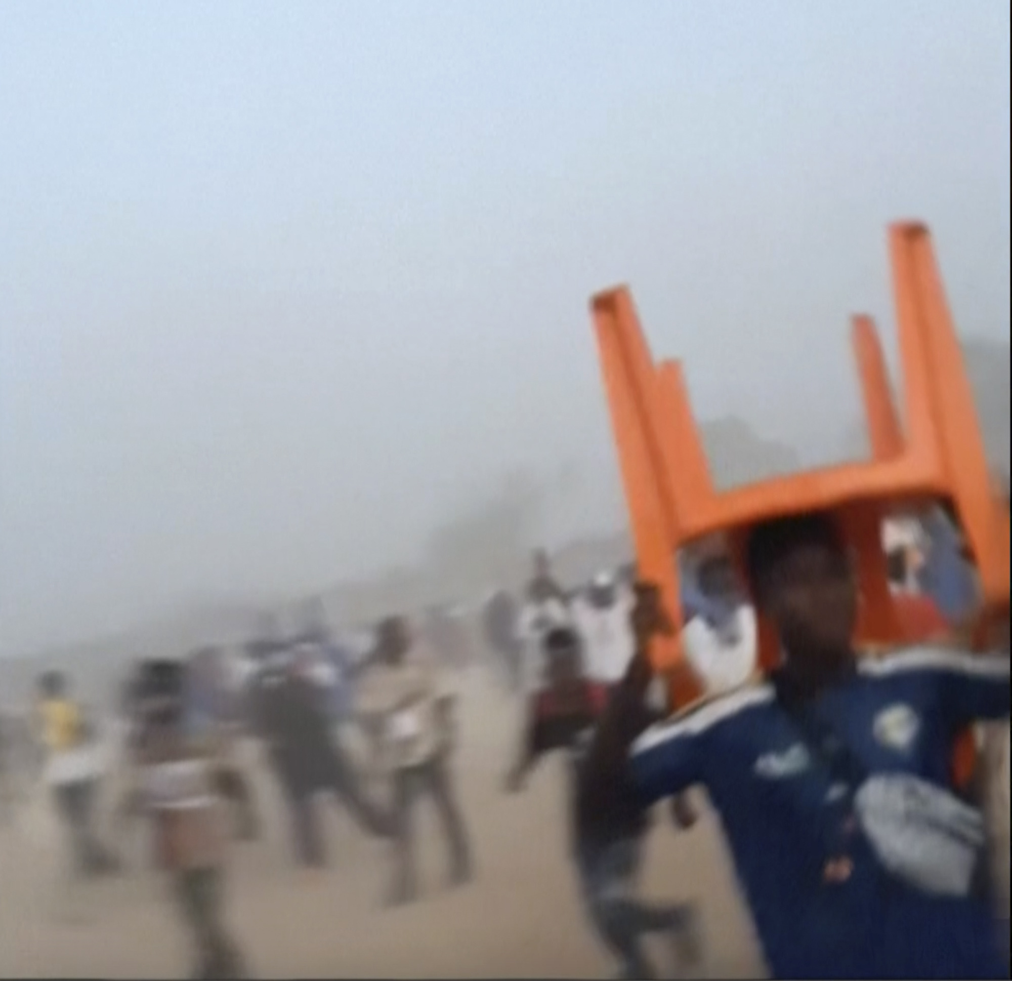 In this grab taken from video provided by Nimba Sports Zaly, a man holds a chair on top of his head in a stampede, during a soccer match at the Stade de Nzérékoré, in Nzérékoré, Guinea on Sunday, Dec. 1, 2024.