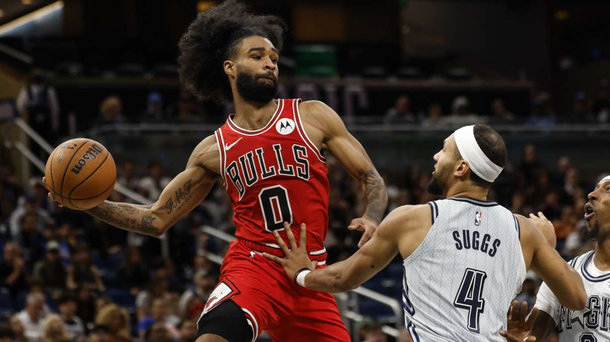 Chicago Bulls guard Coby White (0) pitches ball out from under basket as he is defended by Orlando Magic guard Jalen Suggs (4) during the second half of an NBA basketball game, Wednesday, Nov. 27, 2024, in Orlando, Fla.