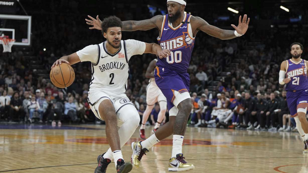 Brooklyn Nets forward Cameron Johnson shields the ball from Phoenix Suns forward Royce O'Neale (00) during the first half of an NBA basketball game, Wednesday, Nov. 27, 2024, in Phoenix.