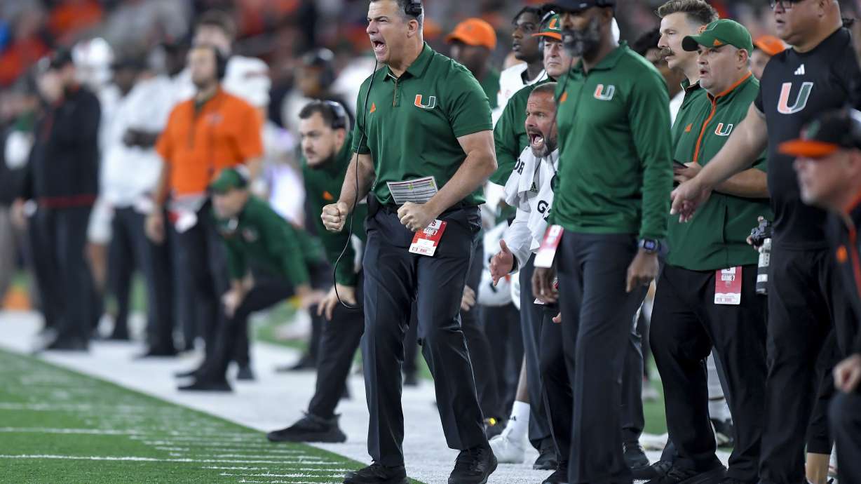 Miami head coach Mario Cristobal, center, urges his team during the first half of an NCAA college football game against Syracuse on Saturday, Nov. 30, 2024 in Syracuse, N.Y.