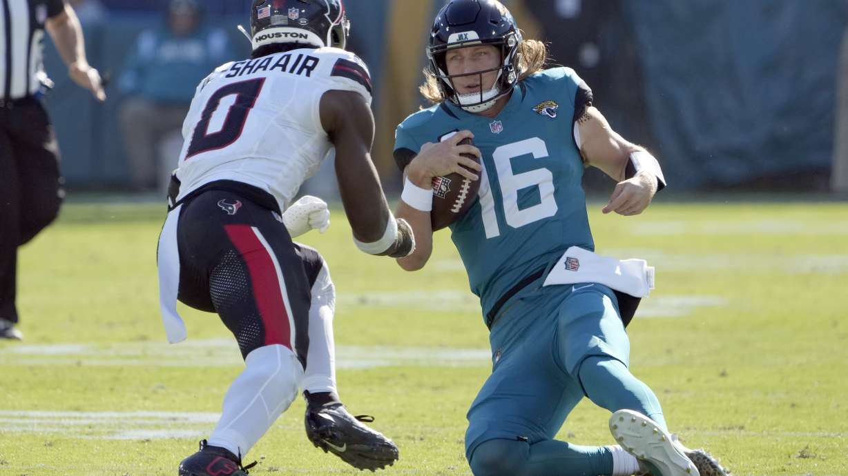 Jacksonville Jaguars quarterback Trevor Lawrence (16) slides in front of Houston Texans linebacker Azeez Al-Shaair (0) during the first half of an NFL football game Sunday, Dec. 1, 2024, in Jacksonville, Fla. Lawrence was injured on the play.
