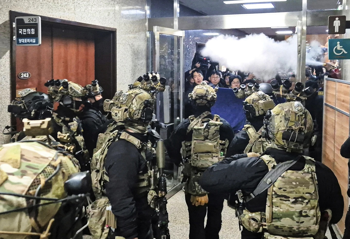 National Assembly staff members spray fire extinguishers to block soldiers from entering the National Assembly in Seoul, South Korea, Wednesday.