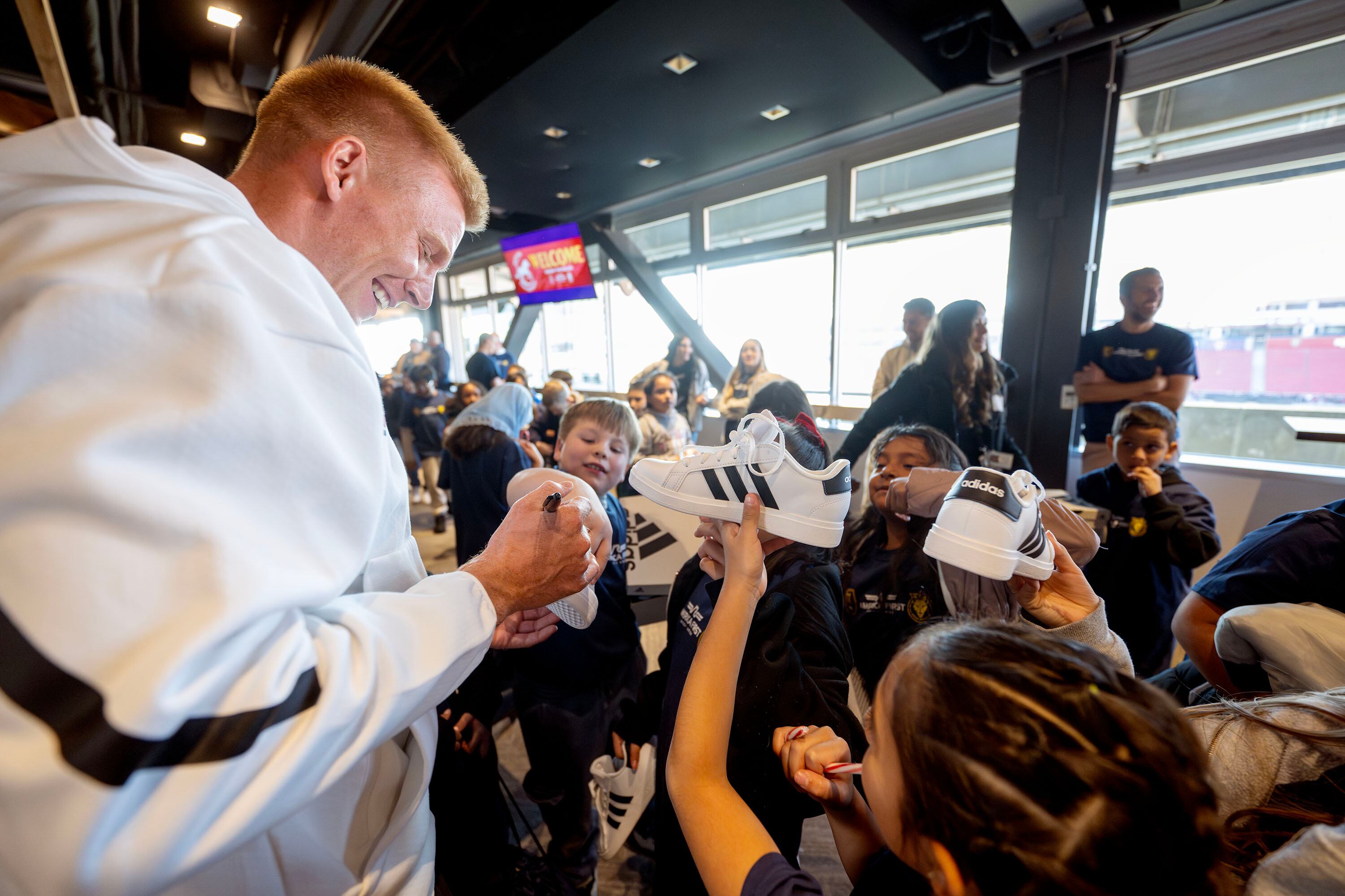 RSL’s Justin Glad signs autographs on some of the kids’ new shoes as America First employees join with RSL as part of the 30th year of the credit union’s “Warm the Soles” tradition. Kids from Midvale Elementary school are given tours of the stadium and field and shoes, in Sandy on Tuesday.