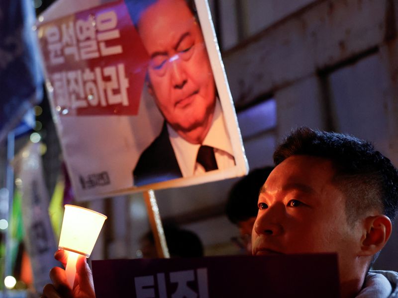 A man holds a placard as people attend a candlelight vigil condemning South Korean President Yoon Suk Yeol's surprise declaration of martial law last night, which was reversed hours later, and to call for his resignation, in Seoul, South Korea, Wednesday.