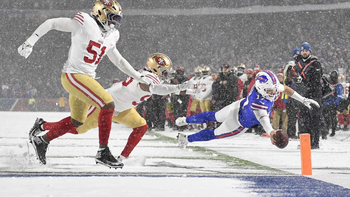 Buffalo Bills quarterback Josh Allen, foreground right, dives toward the end zone to score past San Francisco 49ers defensive end Robert Beal Jr. (51) and linebacker Dee Winters during the second half of an NFL football game in Orchard Park, N.Y., Sunday, Dec. 1, 2024.