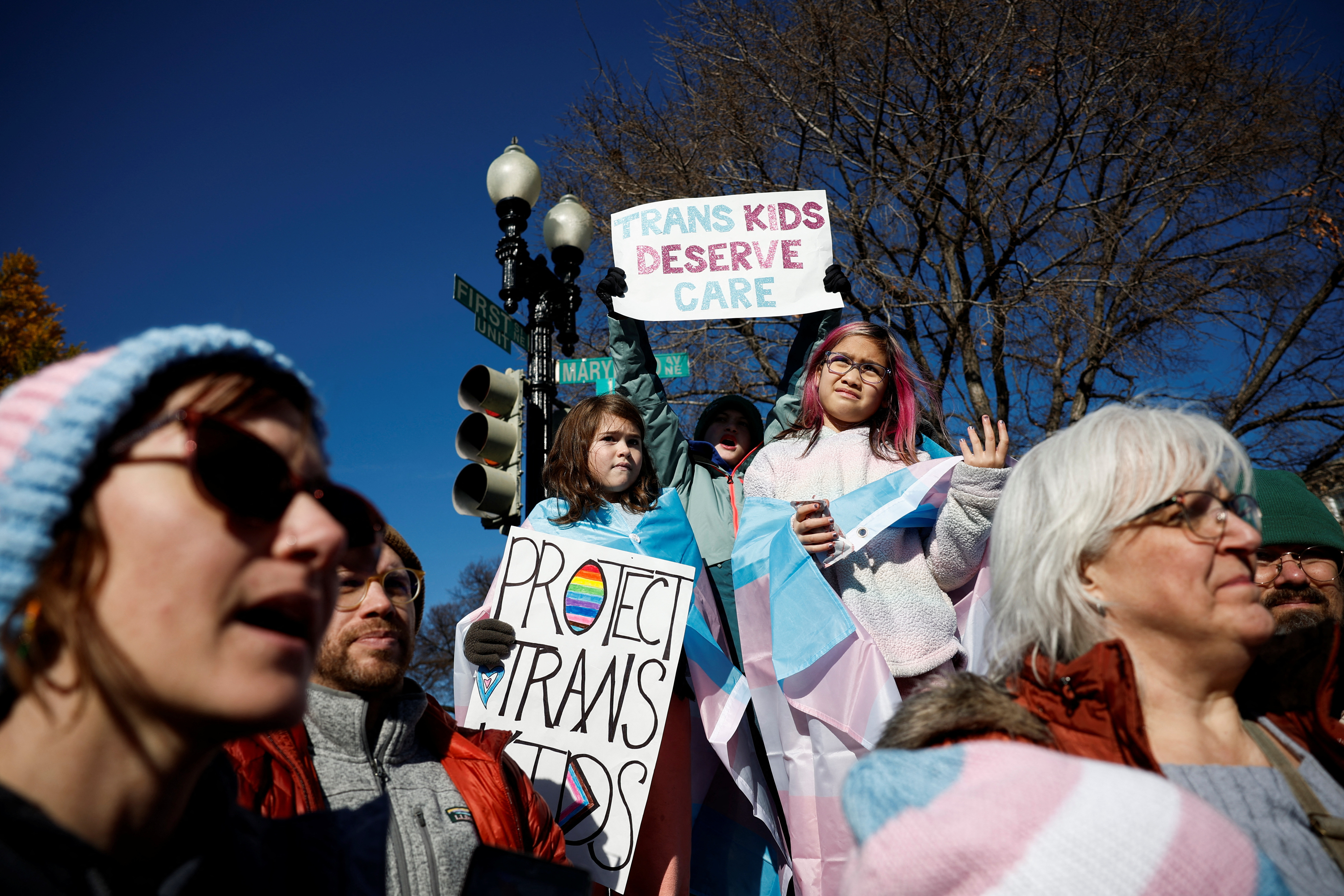 People hold signs as the Supreme Court hears arguments over an appeal by U.S. President Joe Biden's administration of a lower court's decision upholding a Republican-backed ban in Tennessee on gender-related medical care for transgender minors, outside the court in Washington, Wednesday.