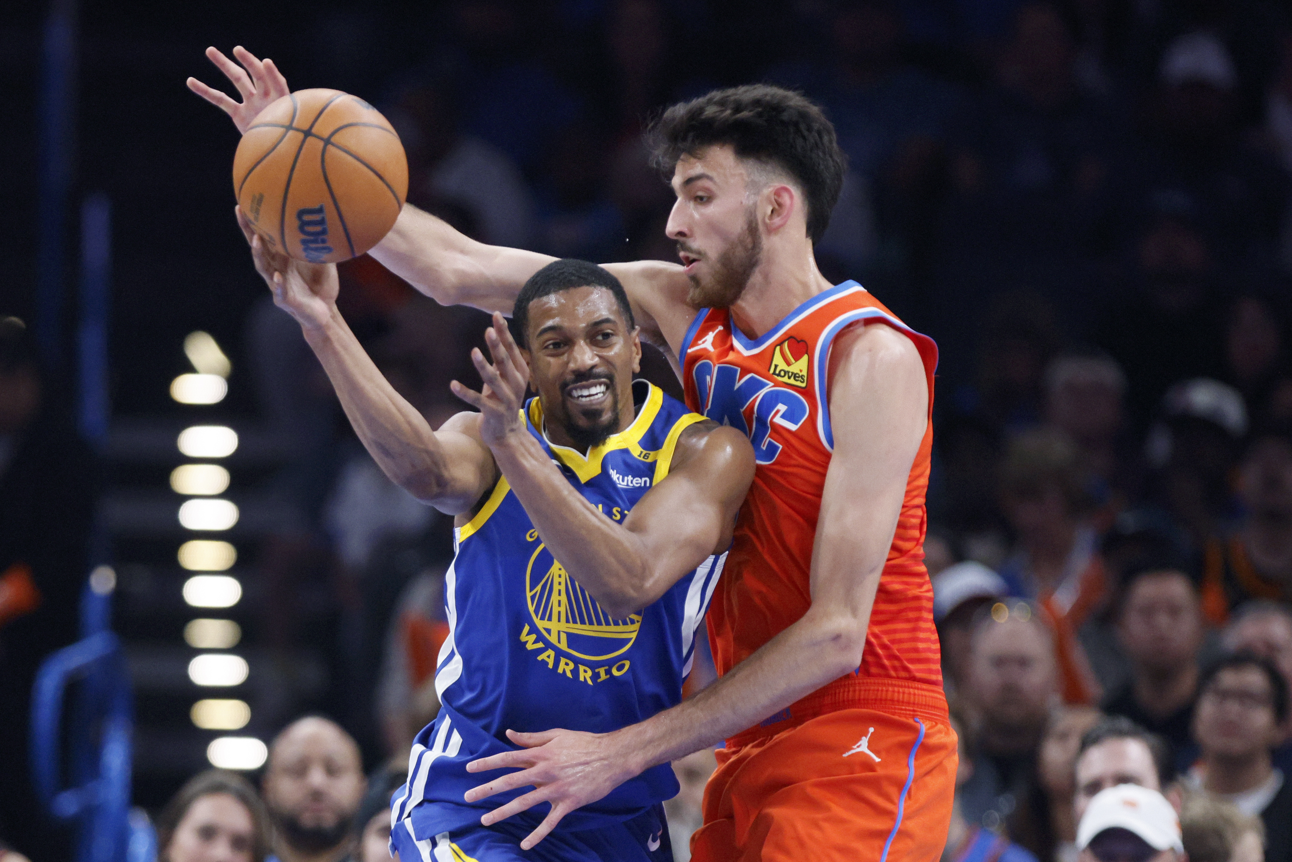 Golden State Warriors guard De'Anthony Melton, left, passes the ball away from Oklahoma City Thunder forward Chet Holmgren, right, during the first half of an NBA basketball game, Sunday, Nov. 10, 2024, in Oklahoma City.