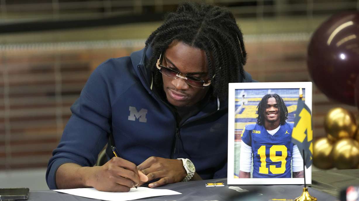 Belleville High School quarterback Bryce Underwood signs to play NCAA football at Michigan during a news conference in Belleville, Mich., Wednesday, Dec. 4, 2024.