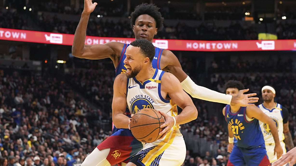 Golden State Warriors guard Stephen Curry, front, drives past Denver Nuggets forward Peyton Watson in the second half of an Emirates NBA Cup basketball game Tuesday, Dec. 3, 2024, in Denver.