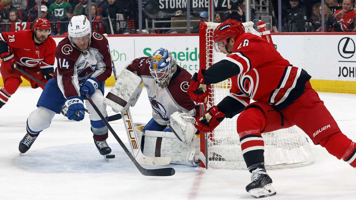 Carolina Hurricanes' Sean Walker (26) has his shot slide past Colorado Avalanche goaltender Scott Wedgewood (41) and Chris Wagner (14) with Hurricanes' William Carrier (28) nearby during the second period of an NHL hockey game in Raleigh, N.C., Thursday, Dec. 5, 2024.