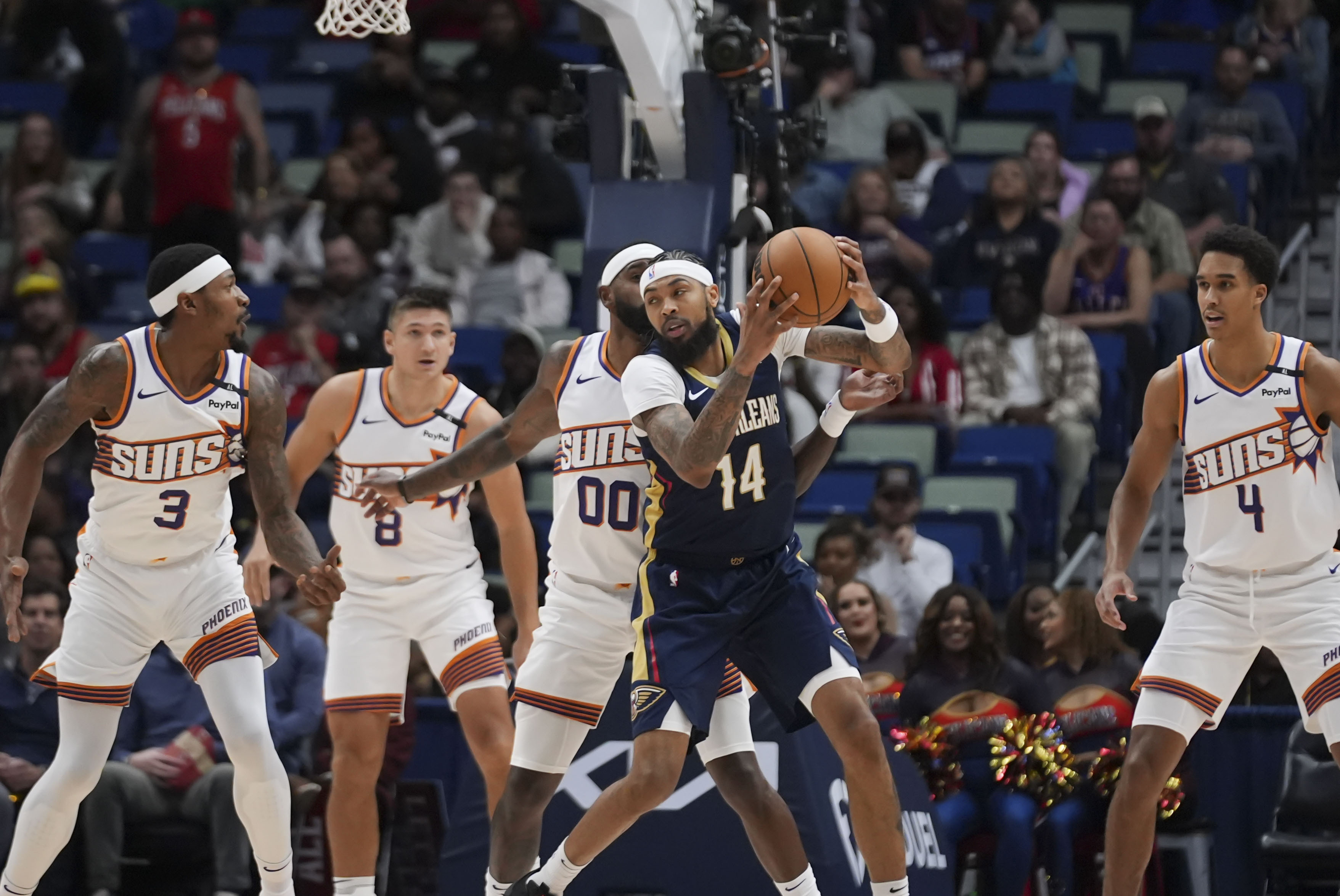 New Orleans Pelicans forward Brandon Ingram (14) looks to pass around Phoenix Suns guard Bradley Beal (3), guard Grayson Allen (8), forward Royce O'Neale (00) and center Oso Ighodaro (4) in the first half of an NBA basketball game in New Orleans, Thursday, Dec. 5, 2024.
