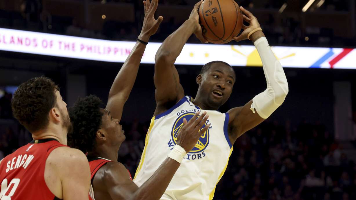 Golden State Warriors forward Jonathan Kuminga (00) is defended by Houston Rockets forward Amen Thompson, center, during the first half of an NBA basketball game in San Francisco, Thursday, Dec. 5, 2024.
