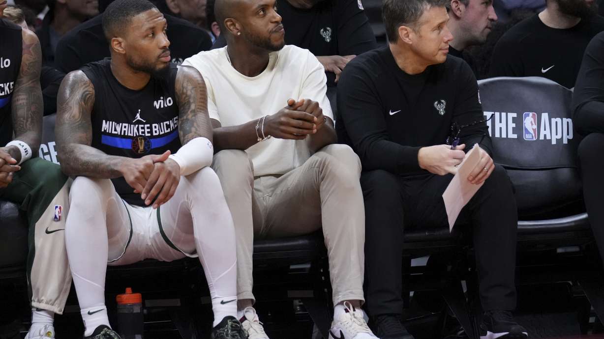 Milwaukee Bucks forward Khris Middleton, center, sits next to guard Damian Lillard, left, during the first half of an Emirates NBA Cup basketball game against the Miami Heat, Tuesday, Nov. 26, 2024, in Miami.