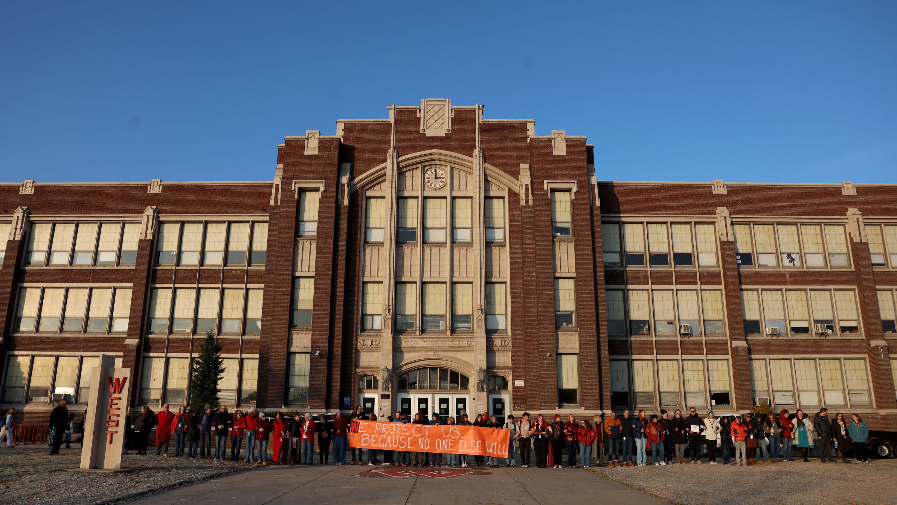 Teachers and staff link arms in solidarity to protest the lack of school safety at West High School in Salt Lake City on Friday, Dec. 6, 2024.