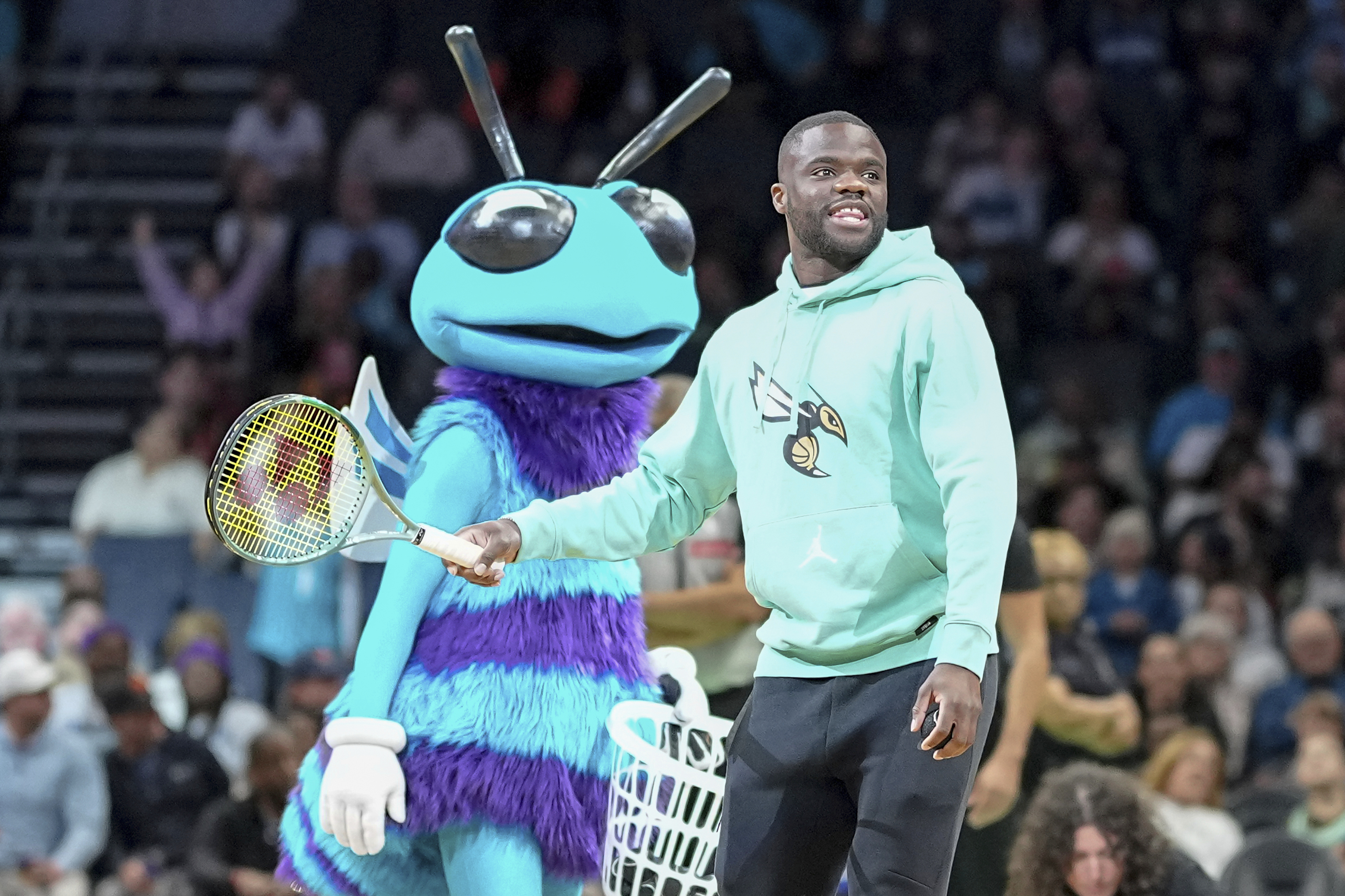Tennis star Frances Tiafoe hits tennis balls into the crowd during a timeout in an NBA basketball game between the Charlotte Hornets and Cleveland Cavaliers, Saturday, Dec. 7, 2024, in Charlotte, N.C.