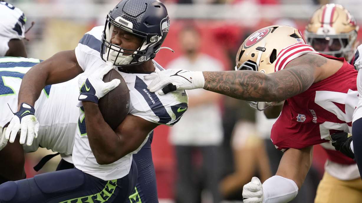 Seattle Seahawks running back Kenneth Walker III, left, runs against San Francisco 49ers defensive end Yetur Gross-Matos during the first half of an NFL football game in Santa Clara, Calif., Sunday, Nov. 17, 2024.