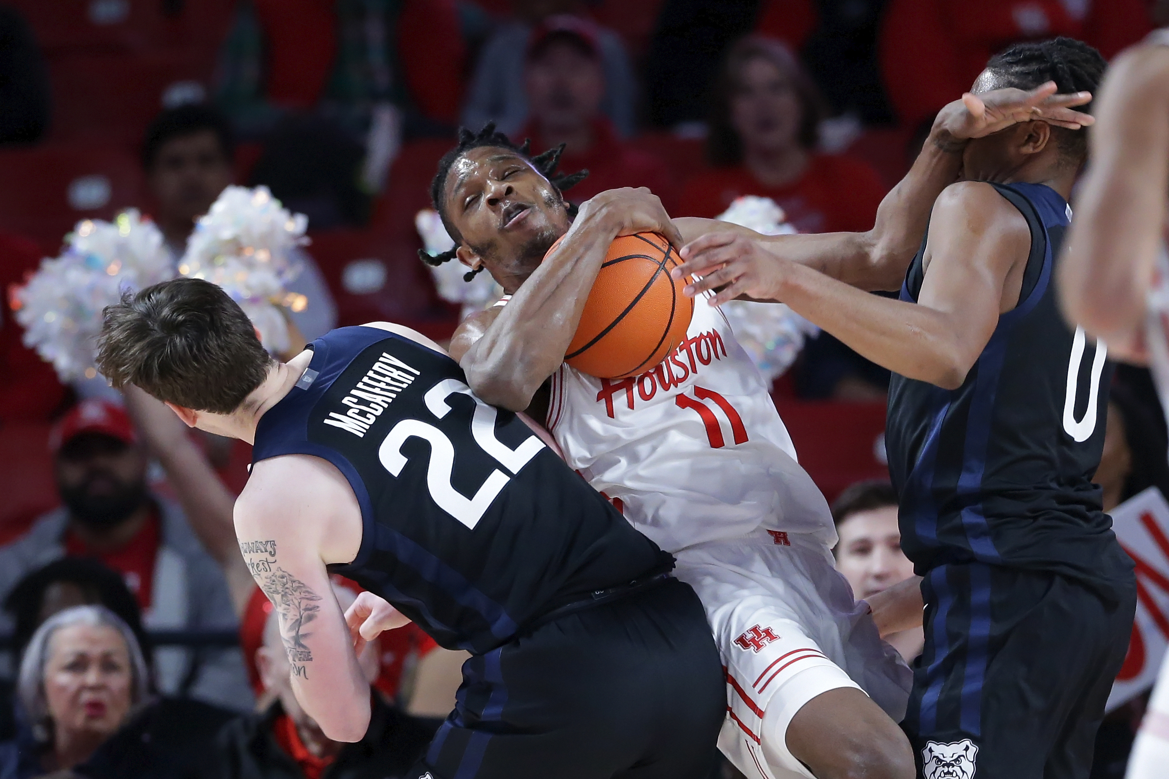 Houston forward Joseph Tugler (11) battles for a rebound between Butler forwards Patrick McCaffery (22) and Augusto Cassia (0) during the first half of an NCAA college basketball game Saturday, Dec. 7, 2024, in Houston.