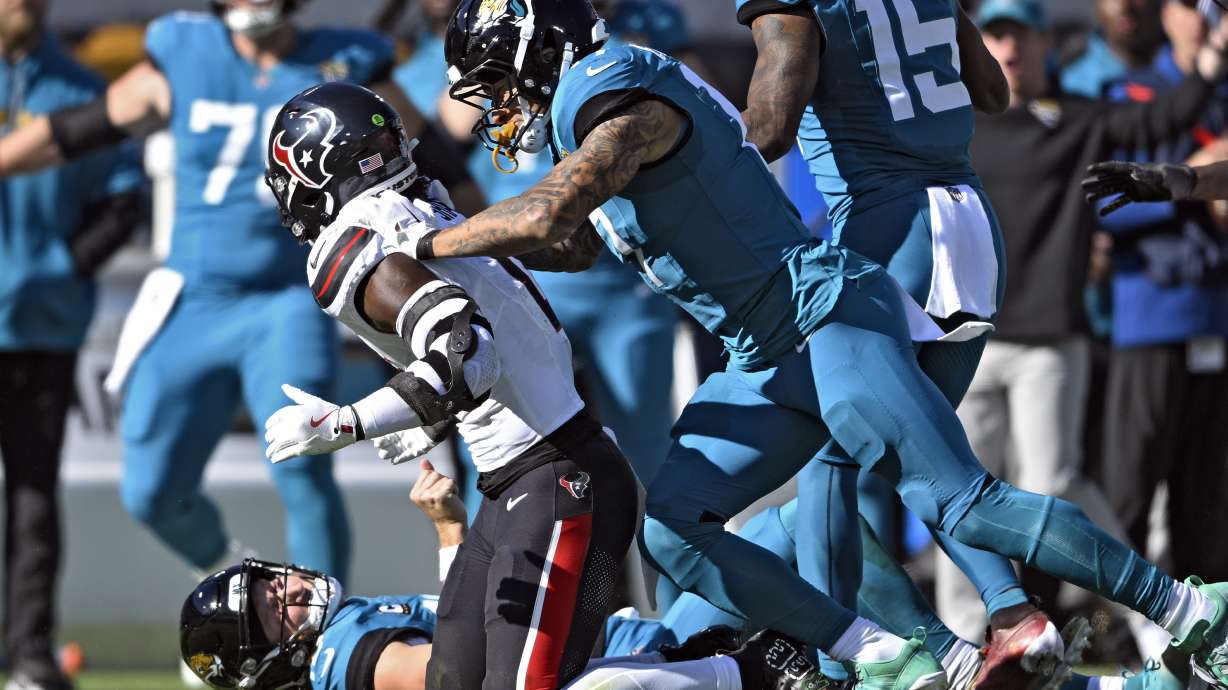 Jacksonville Jaguars tight end Evan Engram (17, right) jumps on Houston Texans linebacker Azeez Al-Shaair (0) after his late hit on quarterback Trevor Lawrence (16) during the first half of an NFL football game Sunday, Dec. 1, 2024, in Jacksonville, Fla.