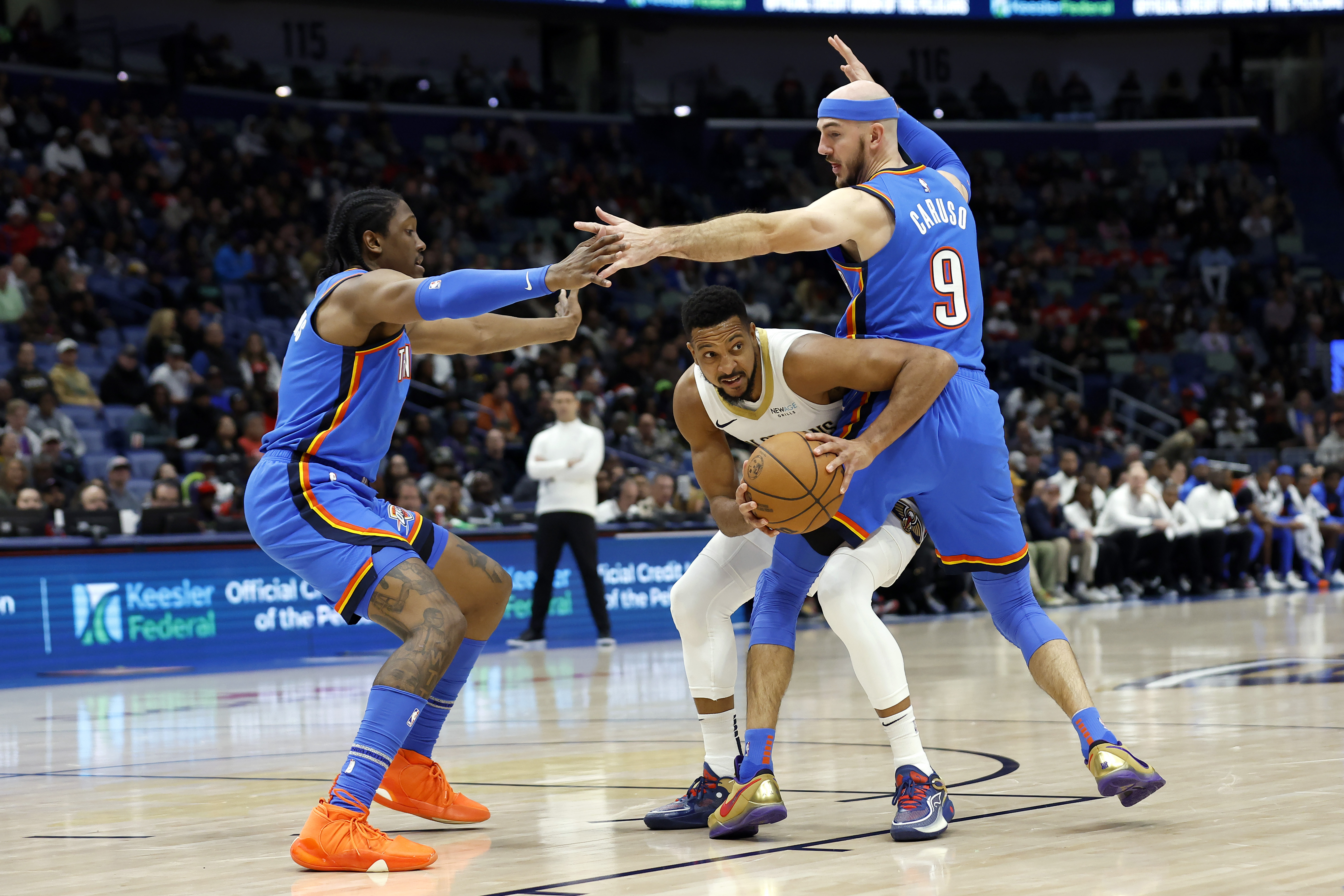 New Orleans Pelicans guard CJ McCollum (3) looks to pass between Oklahoma City Thunder forward Jalen Williams (8) and guard Alex Caruso (9) in the first half of an NBA basketball game in New Orleans, Saturday, Dec. 7, 2024.