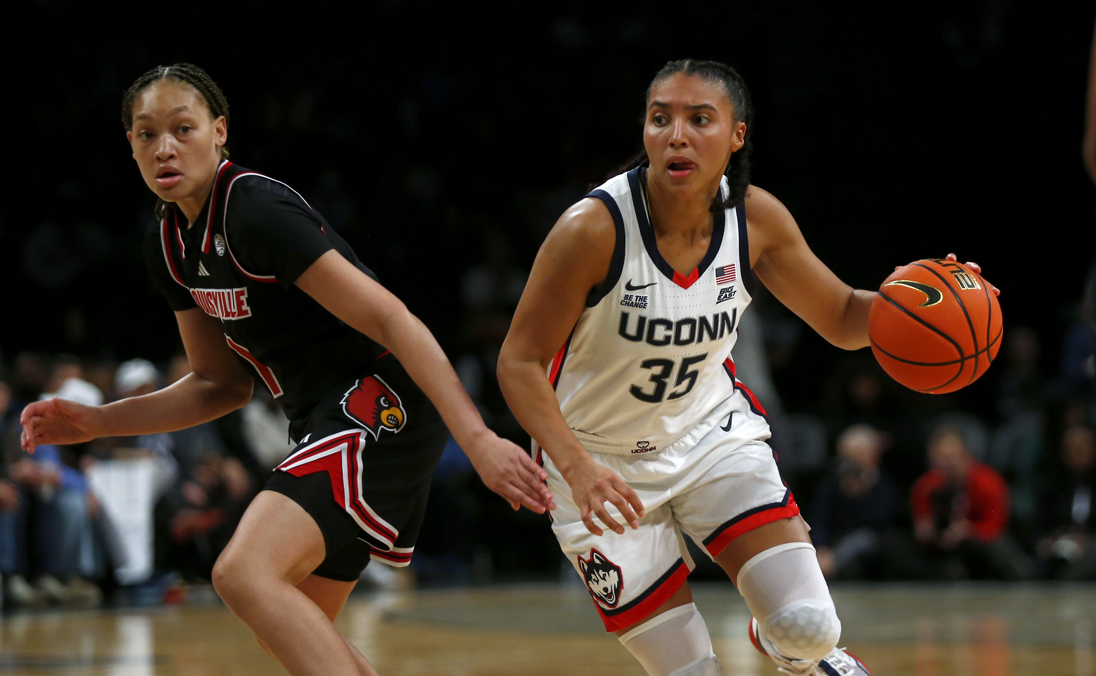 UConn guard Azzi Fudd, right, dribbles around Louisville guard Imary Berry, left, during the first half of an NCAA college basketball game Saturday, Dec. 7, 2024, in New York.