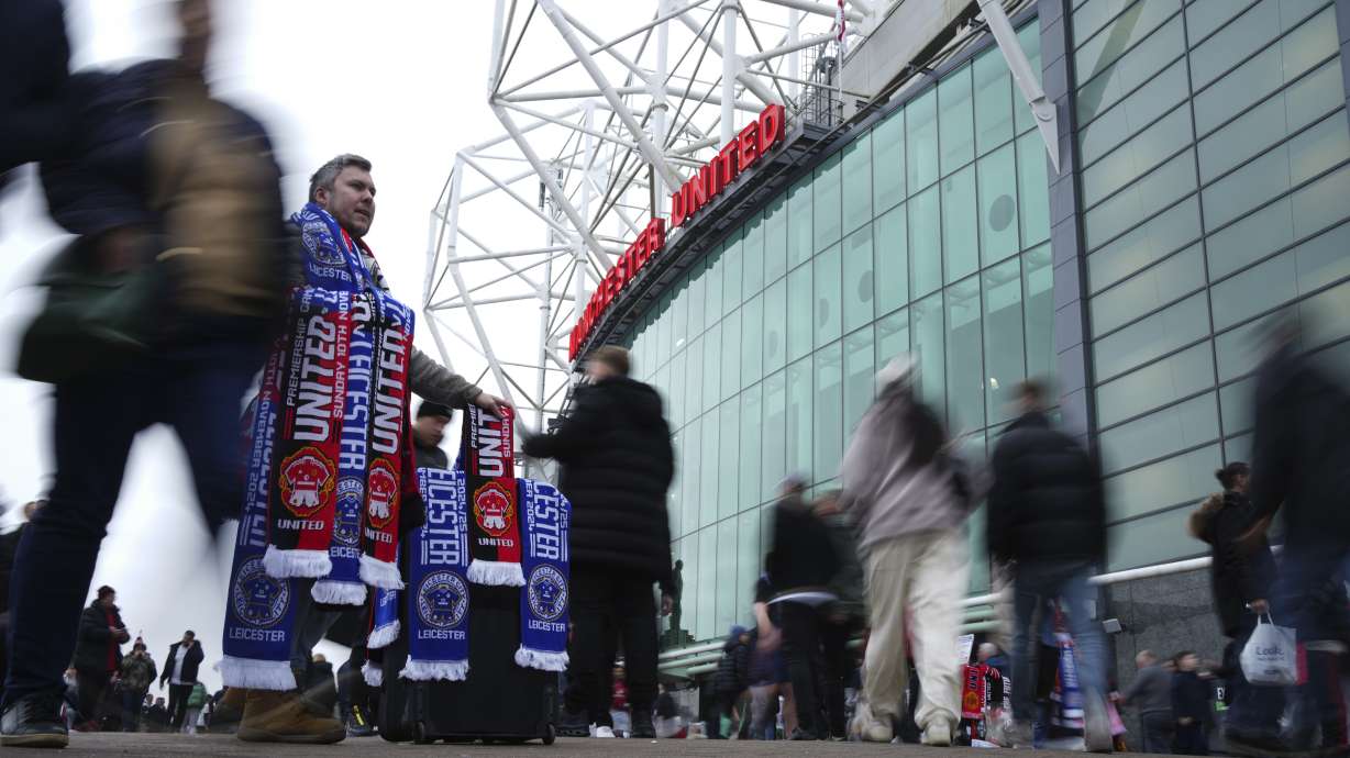 A scarf seller waits for customers prior to the English Premier League soccer match between Manchester United and Leicester City, at the Old Trafford stadium in Manchester, England, Sunday, Nov.10, 2024.