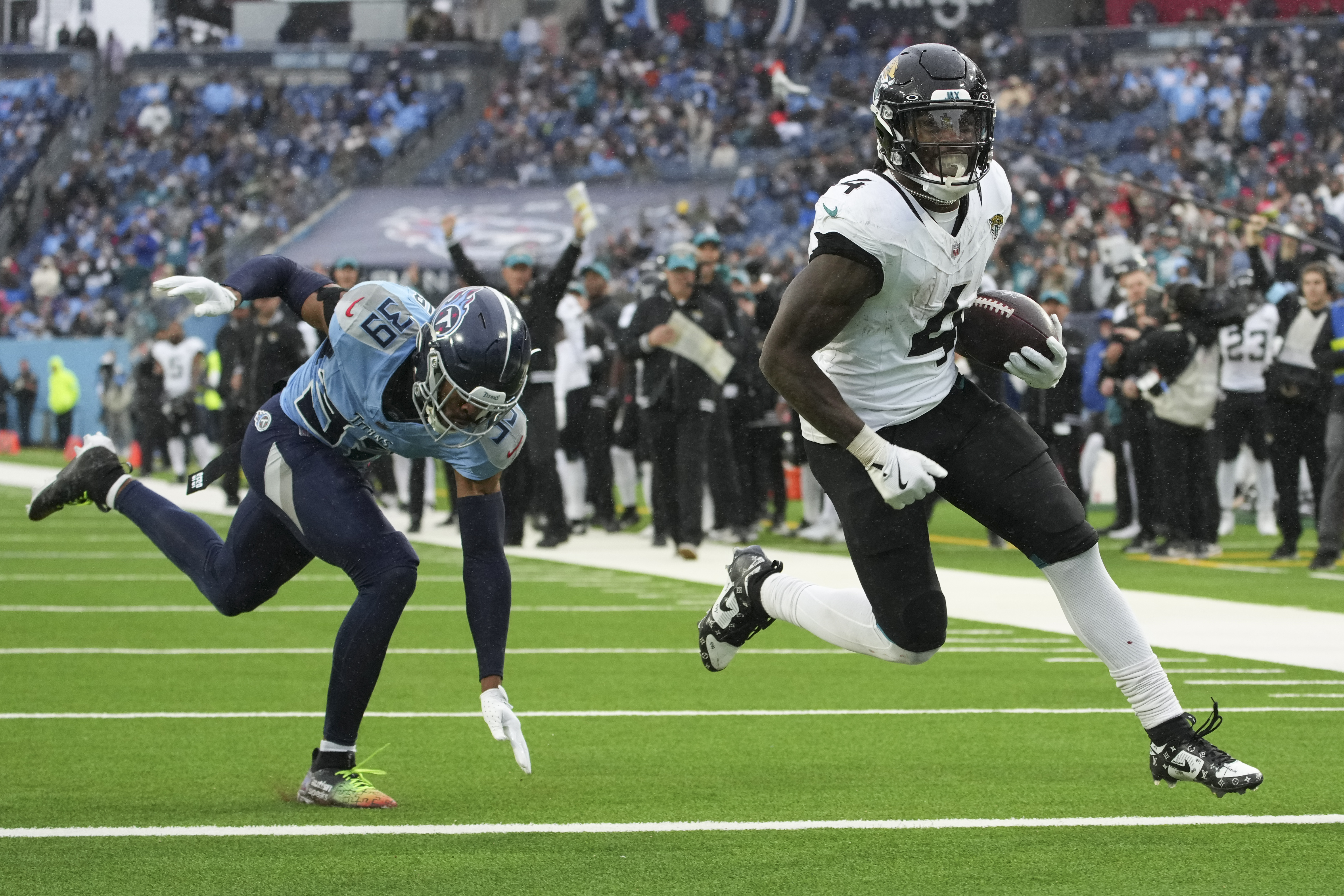 Jacksonville Jaguars running back Tank Bigsby (4) runs for an 8-yard touchdown past Tennessee Titans cornerback Darrell Baker Jr. (39) during the second half of an NFL football game, Sunday, Dec. 8, 2024, in Nashville, Tenn.