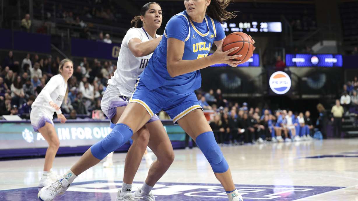 UCLA center Lauren Betts, right, looks to shoot as Washington forward Tayra Eke, center left, defends during the first half of an NCAA college basketball game, Sunday, Dec. 8, 2024, in Seattle.