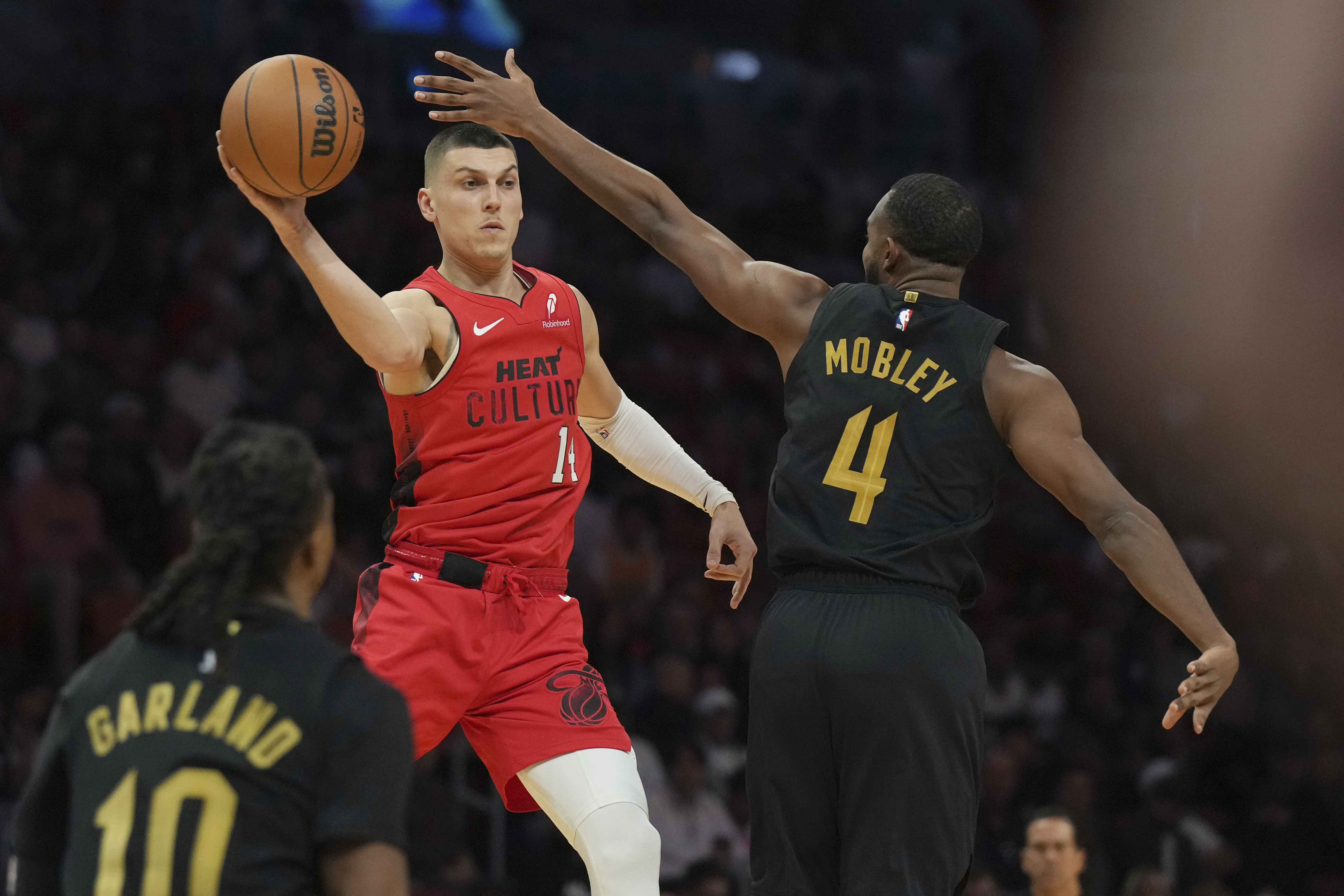 Miami Heat guard Tyler Herro, top left, looks to pass the ball as Cleveland Cavaliers forward Evan Mobley (4) defends during the first half of an NBA basketball game, Sunday, Dec. 8, 2024, in Miami.