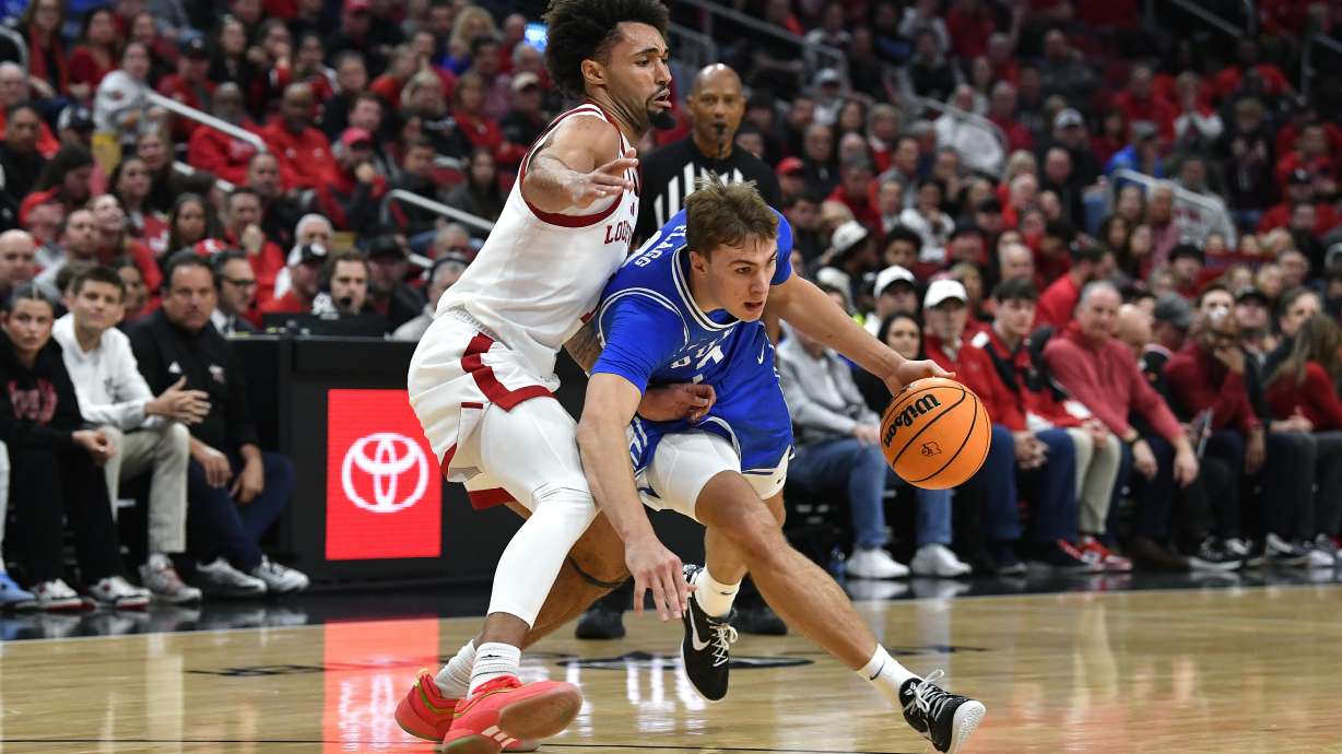 Duke guard Cooper Flagg, right, attempts to get past Louisville guard J'Vonne Hadley, left, during the first half of an NCAA college basketball game in Louisville, Ky., Sunday, Dec. 8, 2024.