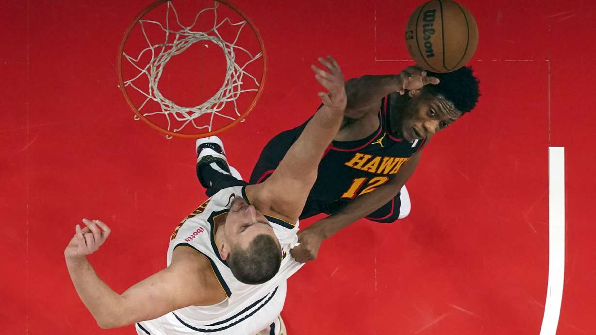 Denver Nuggets center Nikola Jokic (15) and Atlanta Hawks forward De'Andre Hunter (12) battle for a rebound in the first half of an NBA basketball game, Sunday, Dec. 8, 2024, in Atlanta.