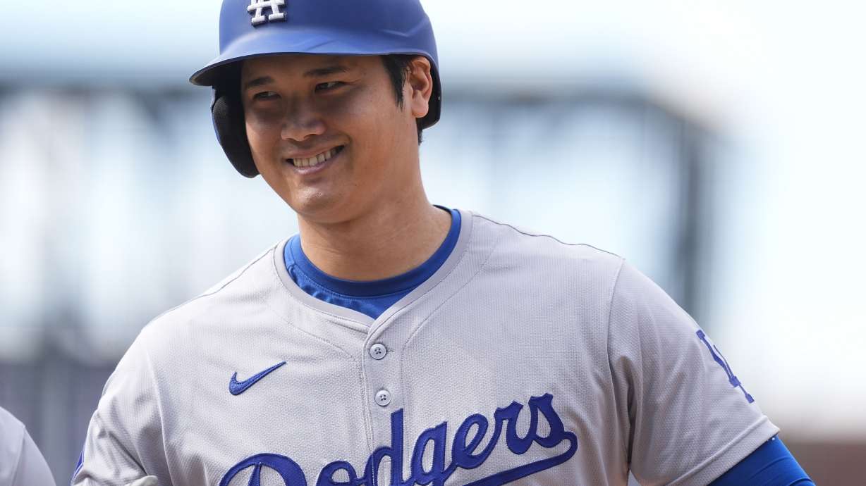 FILE - Los Angeles Dodgers' Shohei Ohtani smiles after reaching first base on a single off Colorado Rockies relief pitcher Seth Halvorsen in the eighth inning of a baseball game Sept. 29, 2024, in Denver.