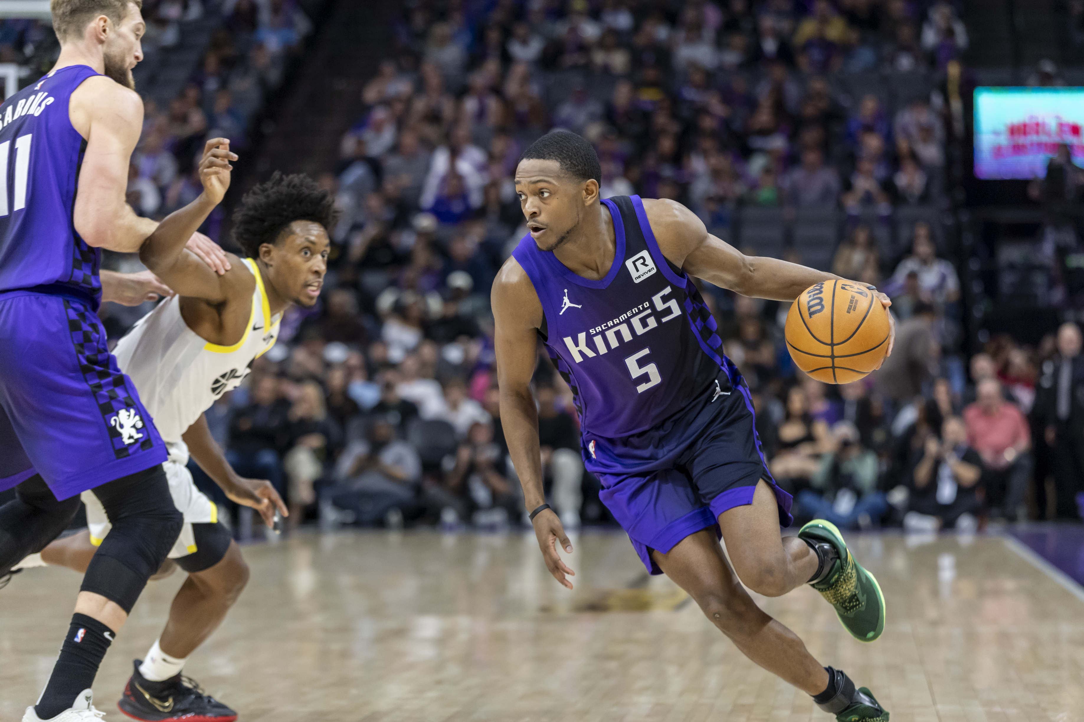 Sacramento Kings guard De'Aaron Fox (5) drives to the basket as Kings forward Domantas Sabonis (11) sets a pick against Utah Jazz guard Collin Sexton, second from left, during the first half of an NBA basketball game Sunday, Dec. 8, 2024, in Sacramento, Calif.