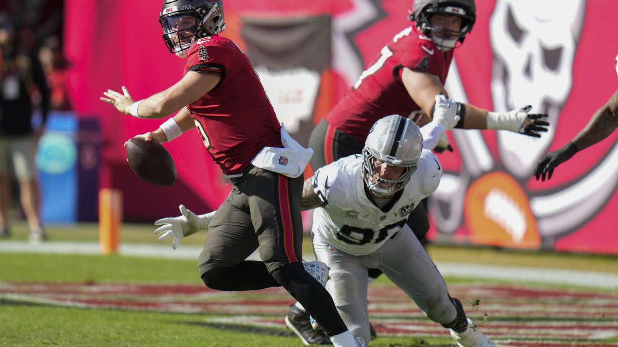Tampa Bay Buccaneers quarterback Baker Mayfield (6) runbs away from Las Vegas Raiders defensive end Maxx Crosby (98) during the first half of an NFL football game, Sunday, Dec. 8, 2024, in Tampa, Fla.