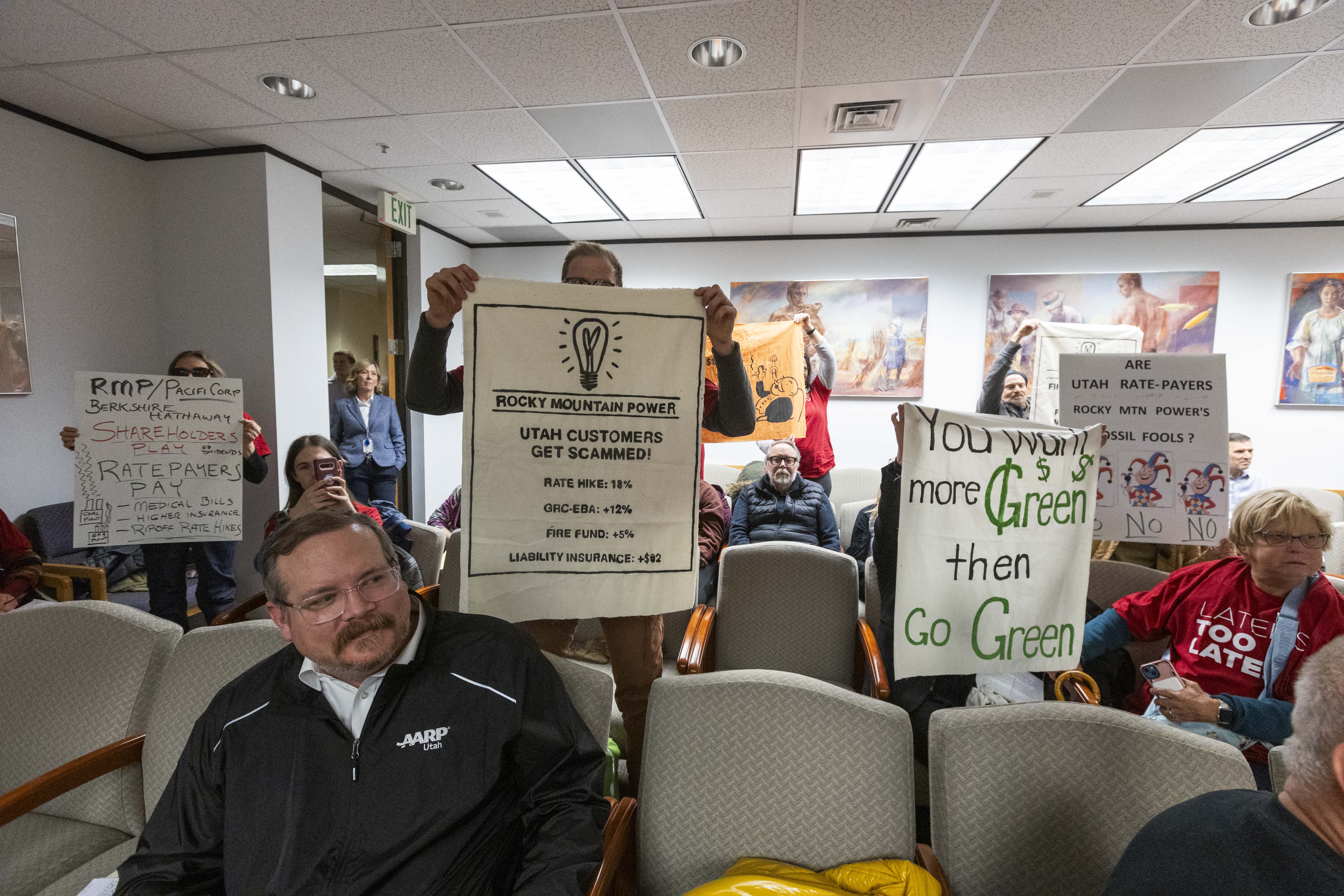 Protesters hold up their signs opposing a rate hike by Rocky Mountain Power at a Utah Public Service Commission’s public hearing in the Heber Wells Building in Salt Lake City on Monday.
