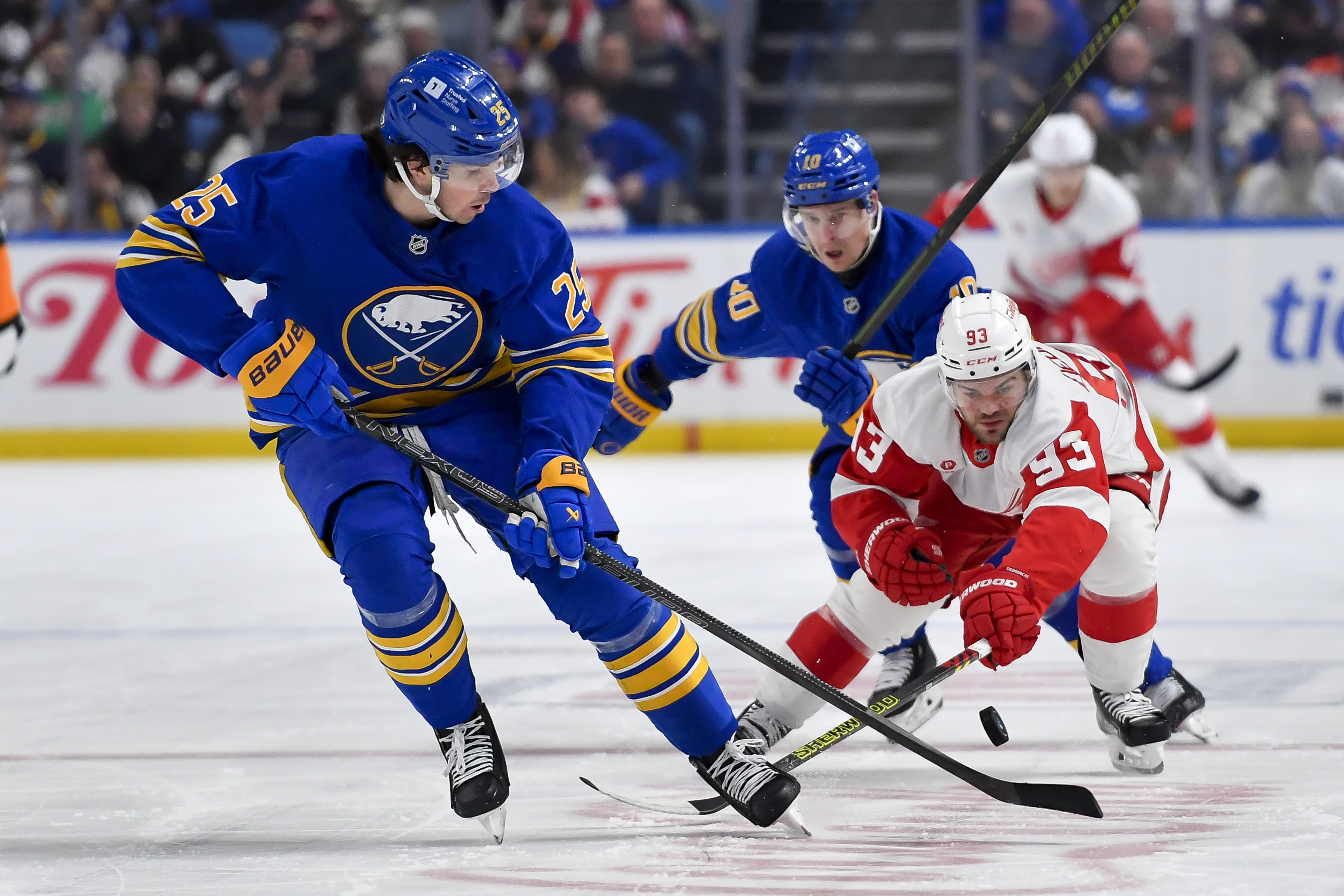 Detroit Red Wings right wing Alex DeBrincat, right, reaches for the puck against Buffalo Sabres defenseman Owen Power during the first period of an NHL hockey game in Buffalo, N.Y., Monday, Dec. 9, 2024.