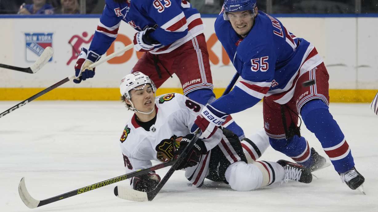 New York Rangers' Ryan Lindgren (55) fights for position with Chicago Blackhawks' Connor Bedard during the first period of an NHL hockey game, Monday, Dec. 9, 2024, in New York.