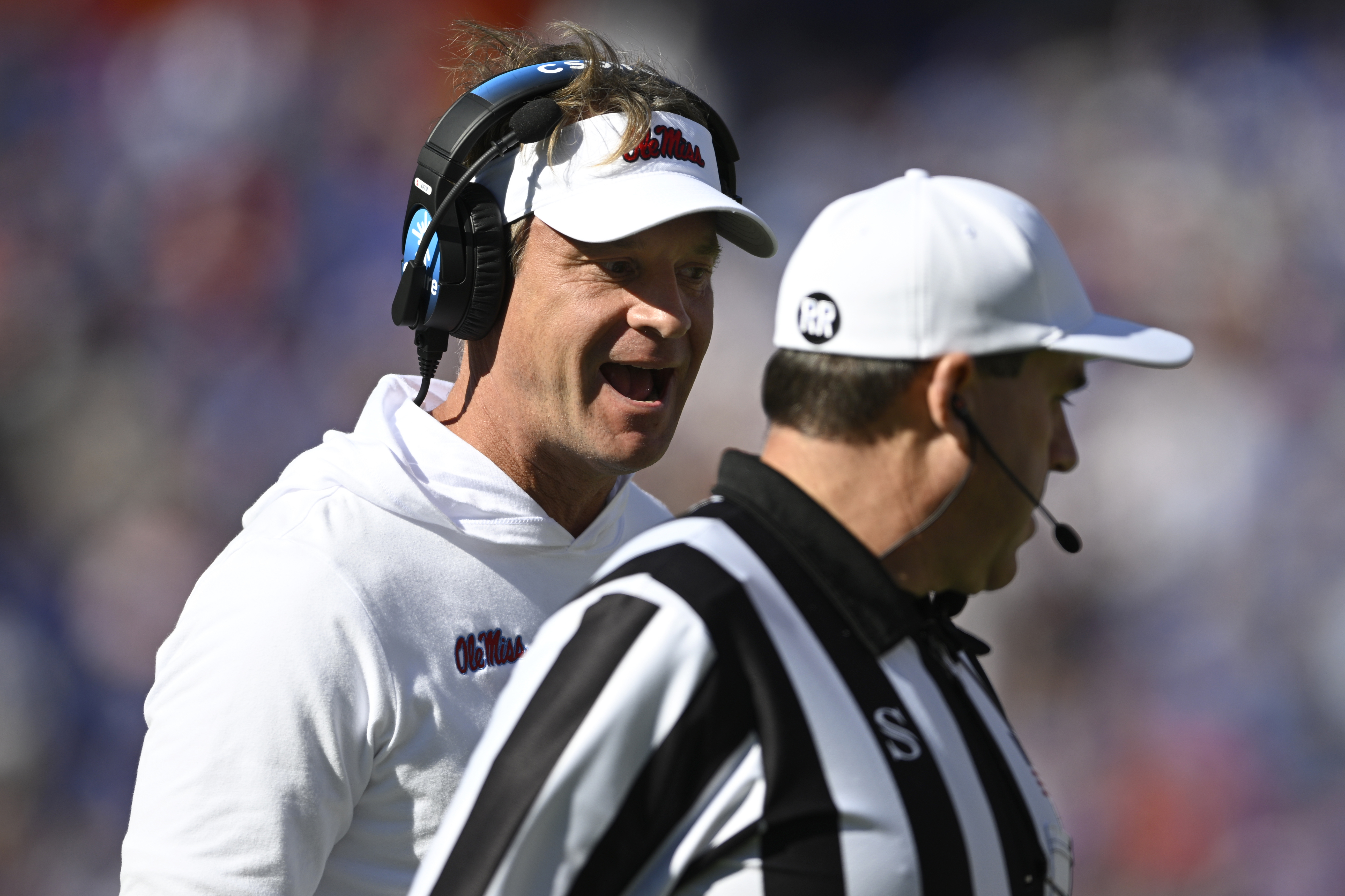 Mississippi head coach Lane Kiffin, left, questions an official on the sideline during the first half of an NCAA college football game against Florida, Saturday, Nov. 23, 2024, in Gainesville, Fla.