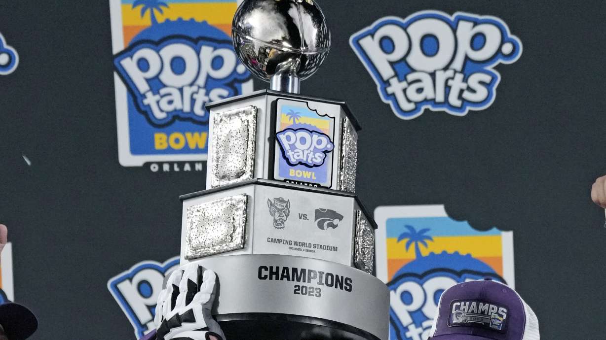 Kansas State players hold up the championship trophy after winning the Pop-Tarts Bowl NCAA college football game against North Carolina State, Thursday, Dec. 28, 2023, in Orlando, Fla.
