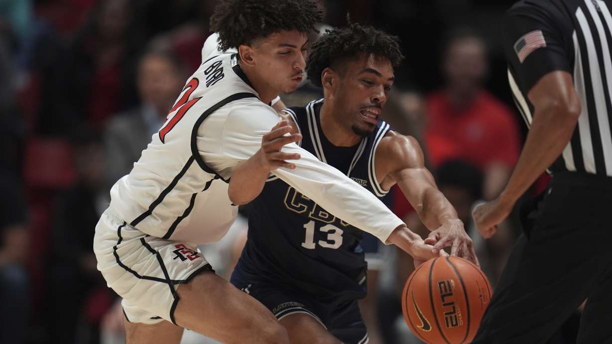 California Baptist guard Javonte Johnson (13) battles San Diego State guard Miles Byrd for a loose ball during the first half of an NCAA college basketball game Wednesday, Dec. 11, 2024, in San Diego.